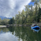 A bear wades into the water while a raft drifts past