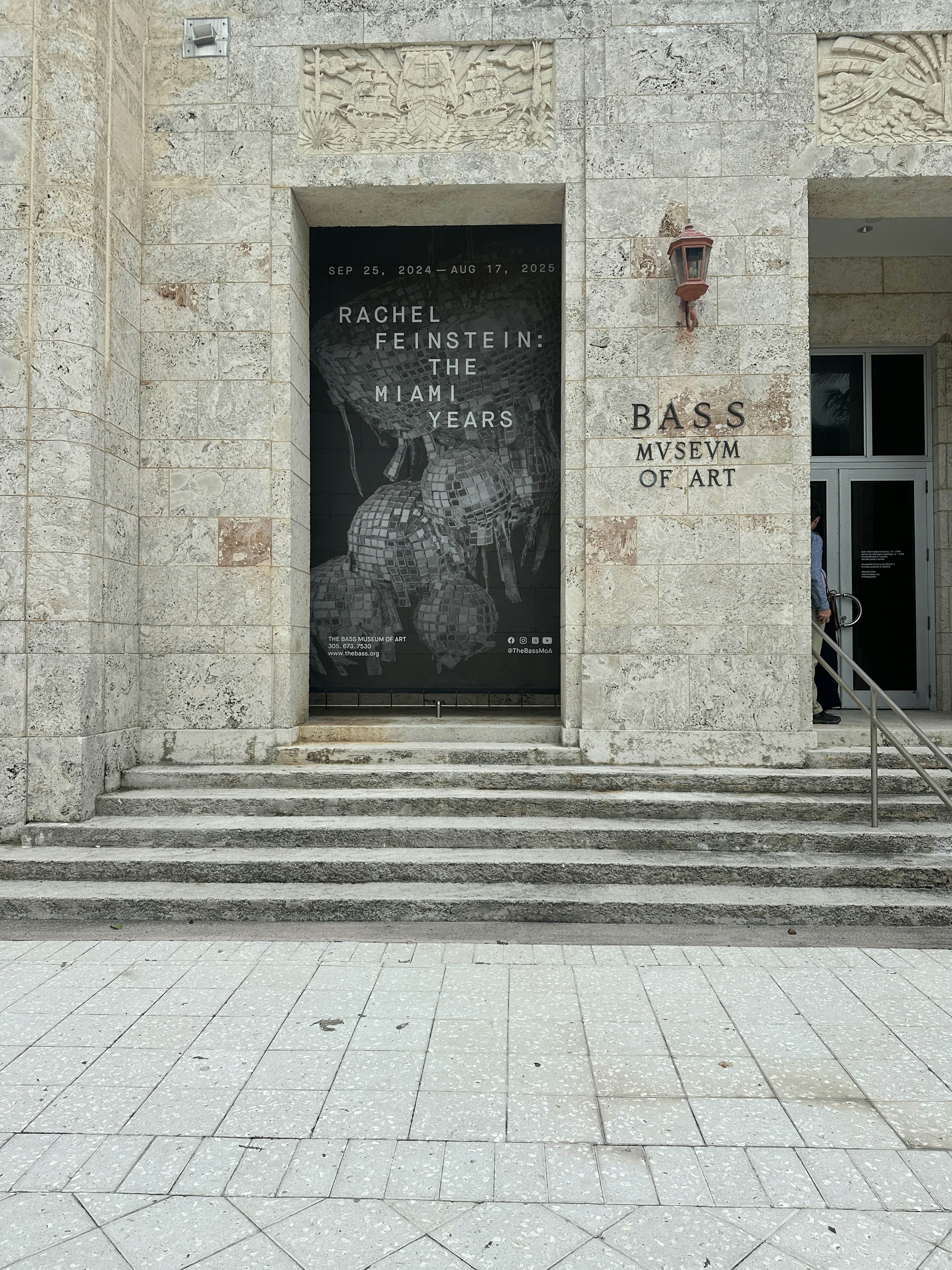 Exterior of the Bass Museum of Art, Miami, with a poster showing the dates of the Rachel Feinstein exhibition, running until August 2025