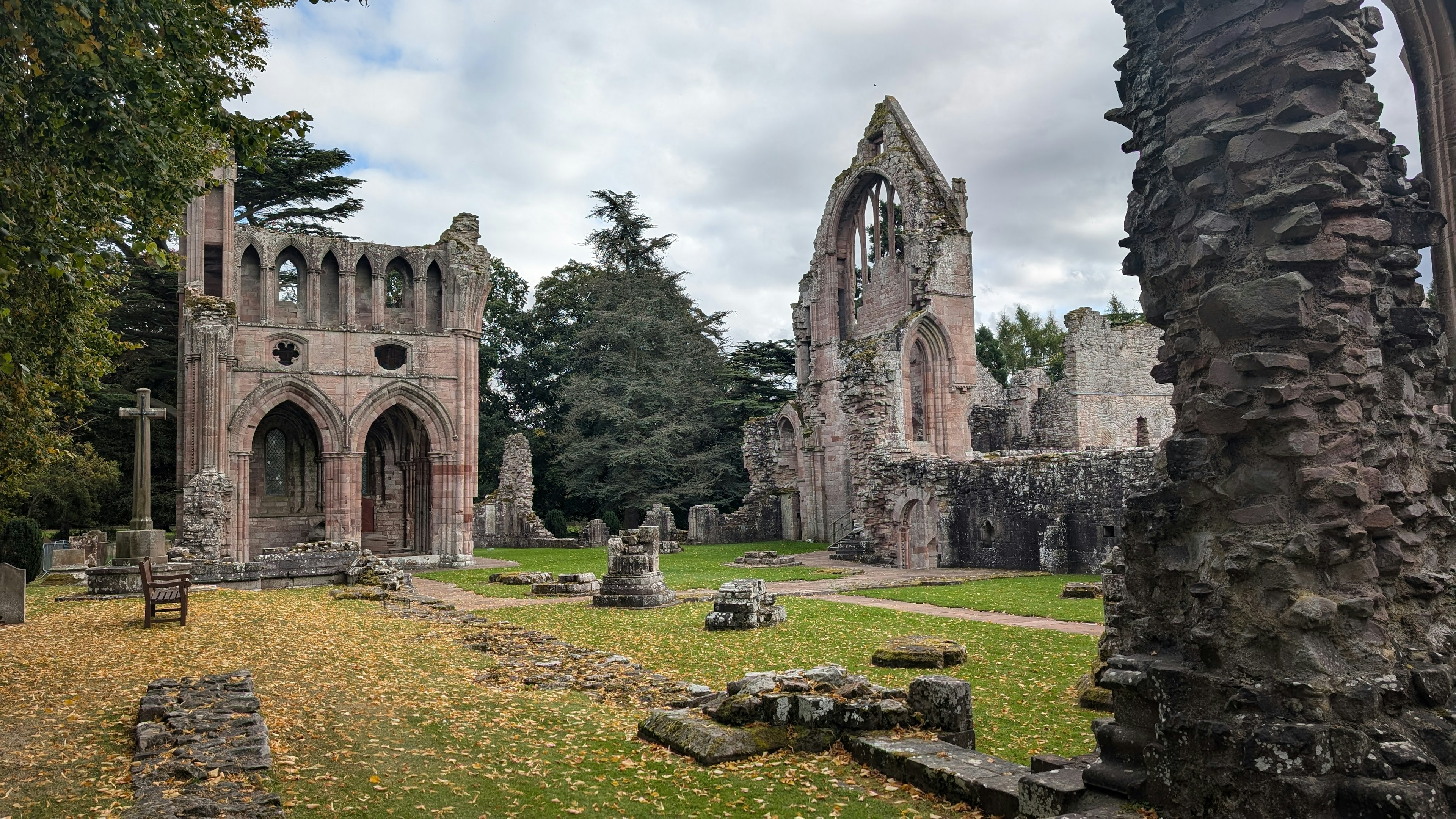 A ruined abbey with some graves and tombs surrounded by woodland