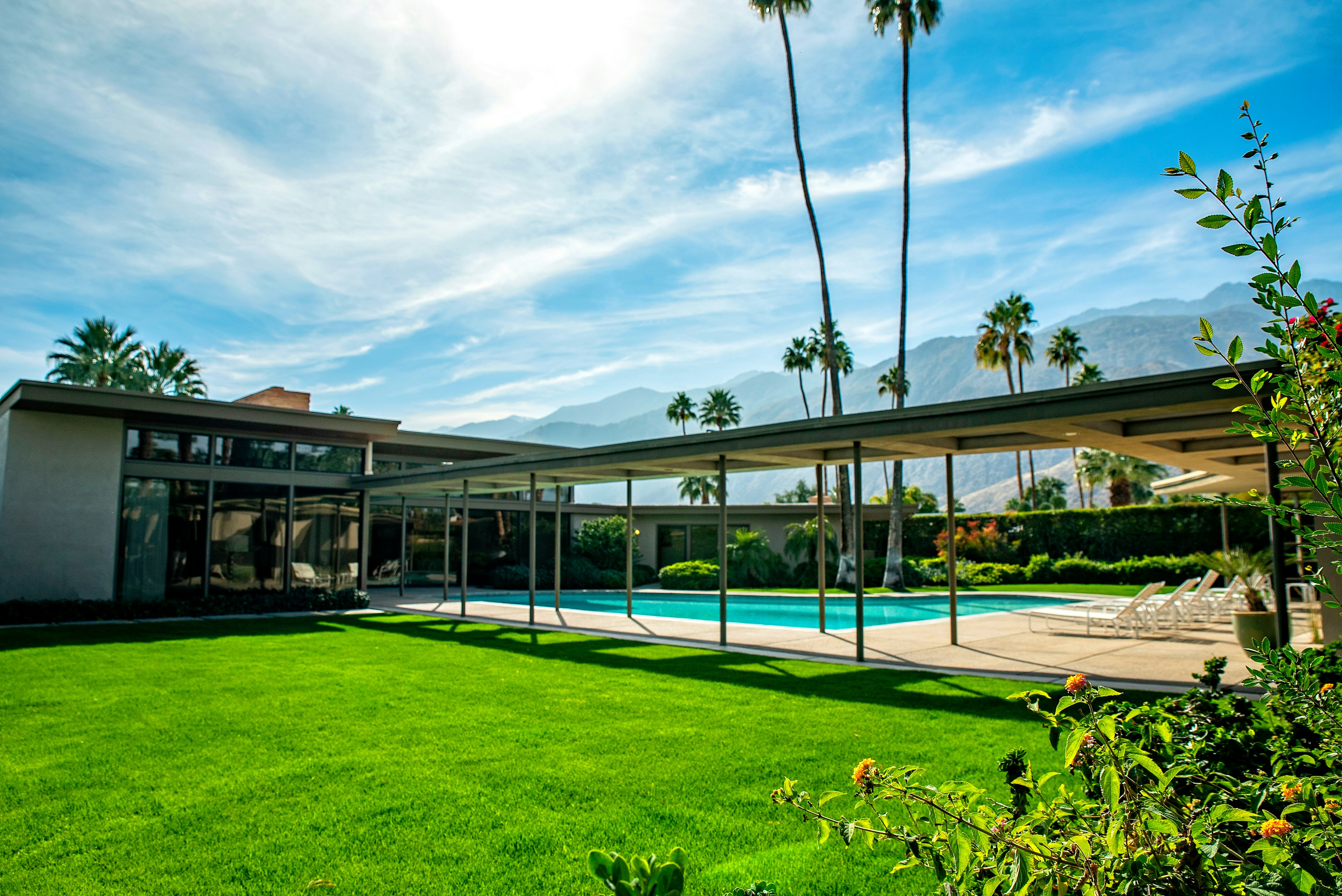 The modernist exterior of Frank Sinatra's home in Greater Palm Springs. Two tall trees rise above a pool shaped like a piano.