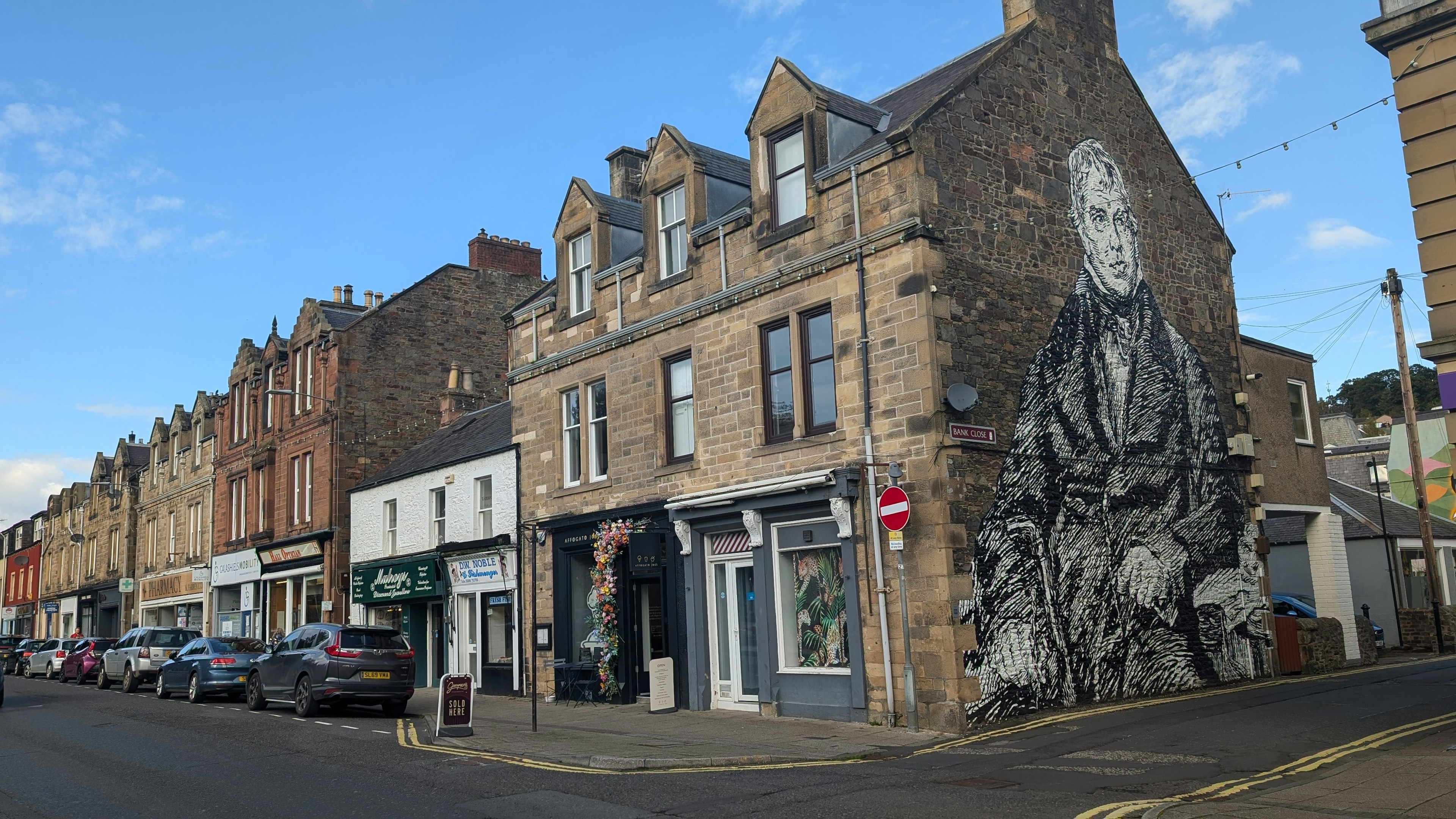 A large black and white mural of a man painted on the side of a building along a main street