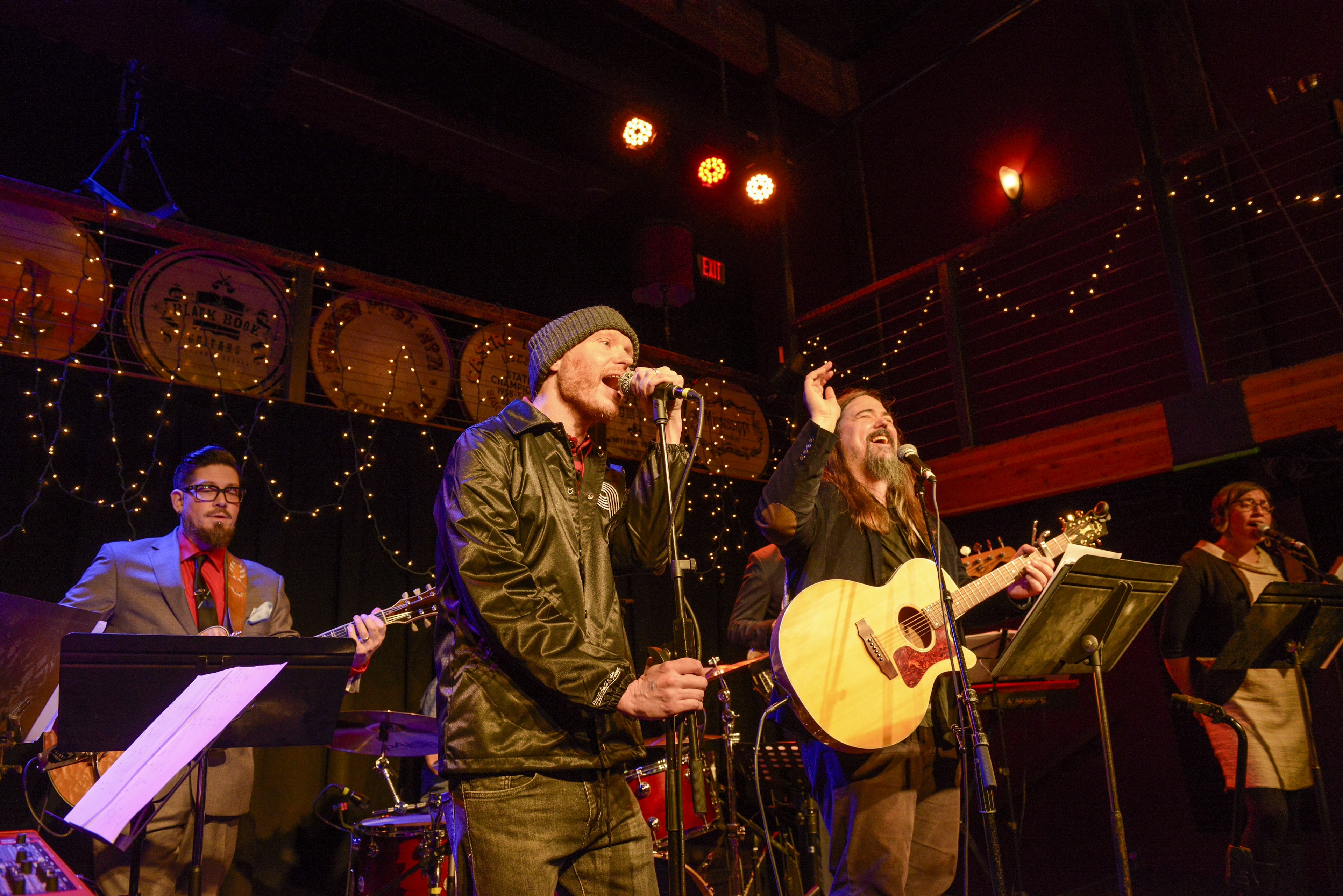 A singer, guitarist and other musicians perform on a stage with strings of lights behind them at Mississippi Studios in Portland, Oregon, USA