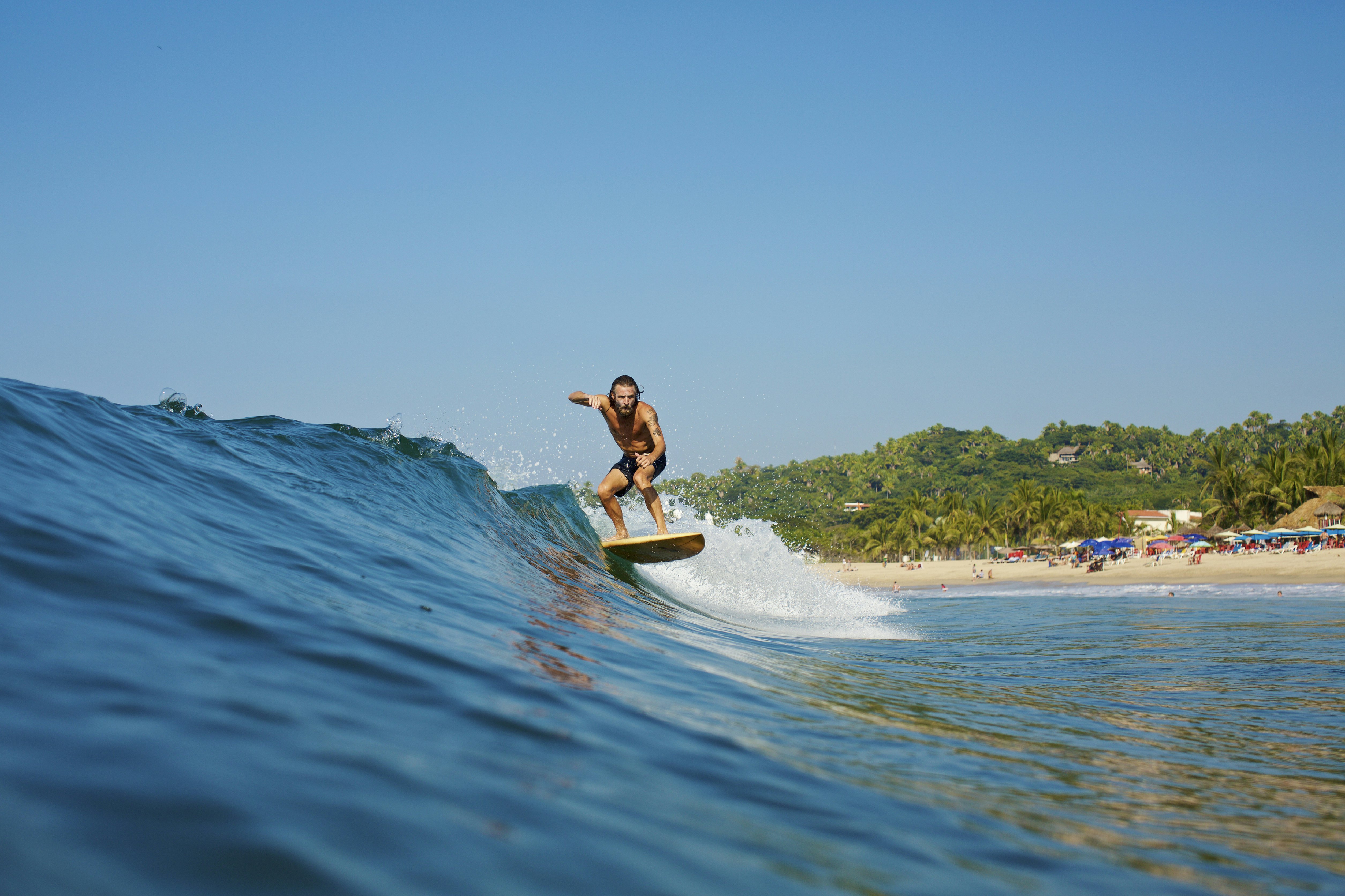 A male surfer rides a wave off the coast of, Sayulita, Nayarit, Mexico