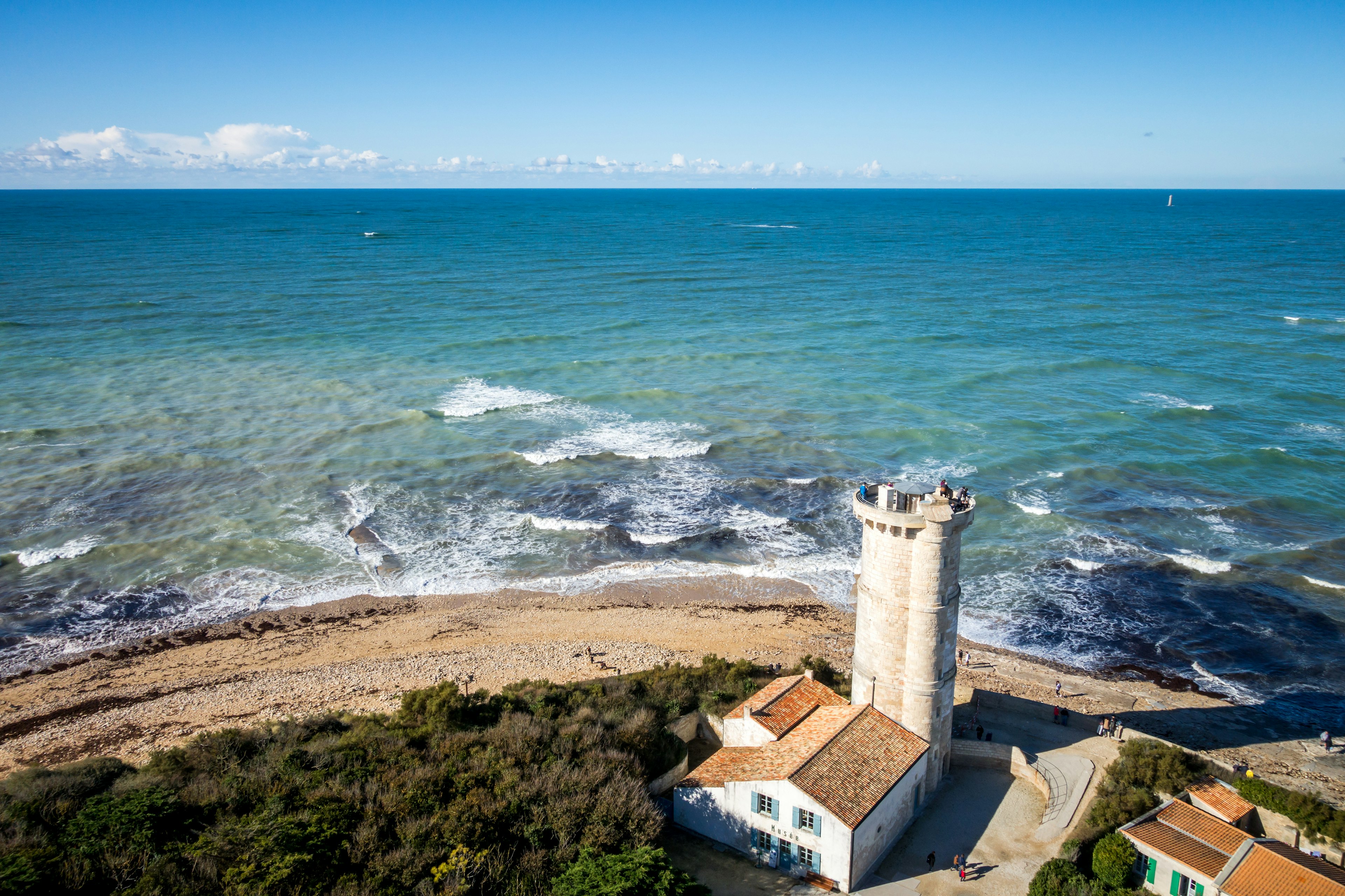 A stone lighthouse on a bend in the shore with the waves crashing below