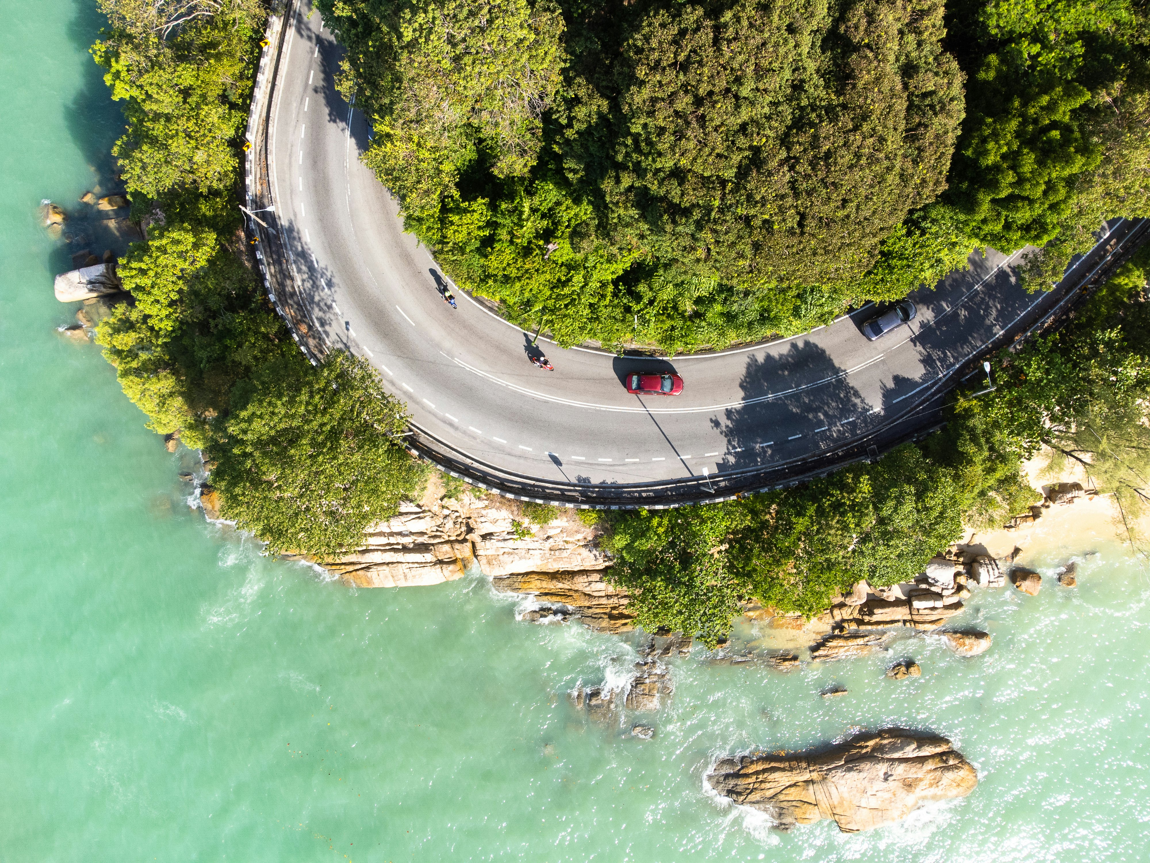 Top down view of a car driving on the coastal road in Batu Ferringhi in the Penang island in Malaysia