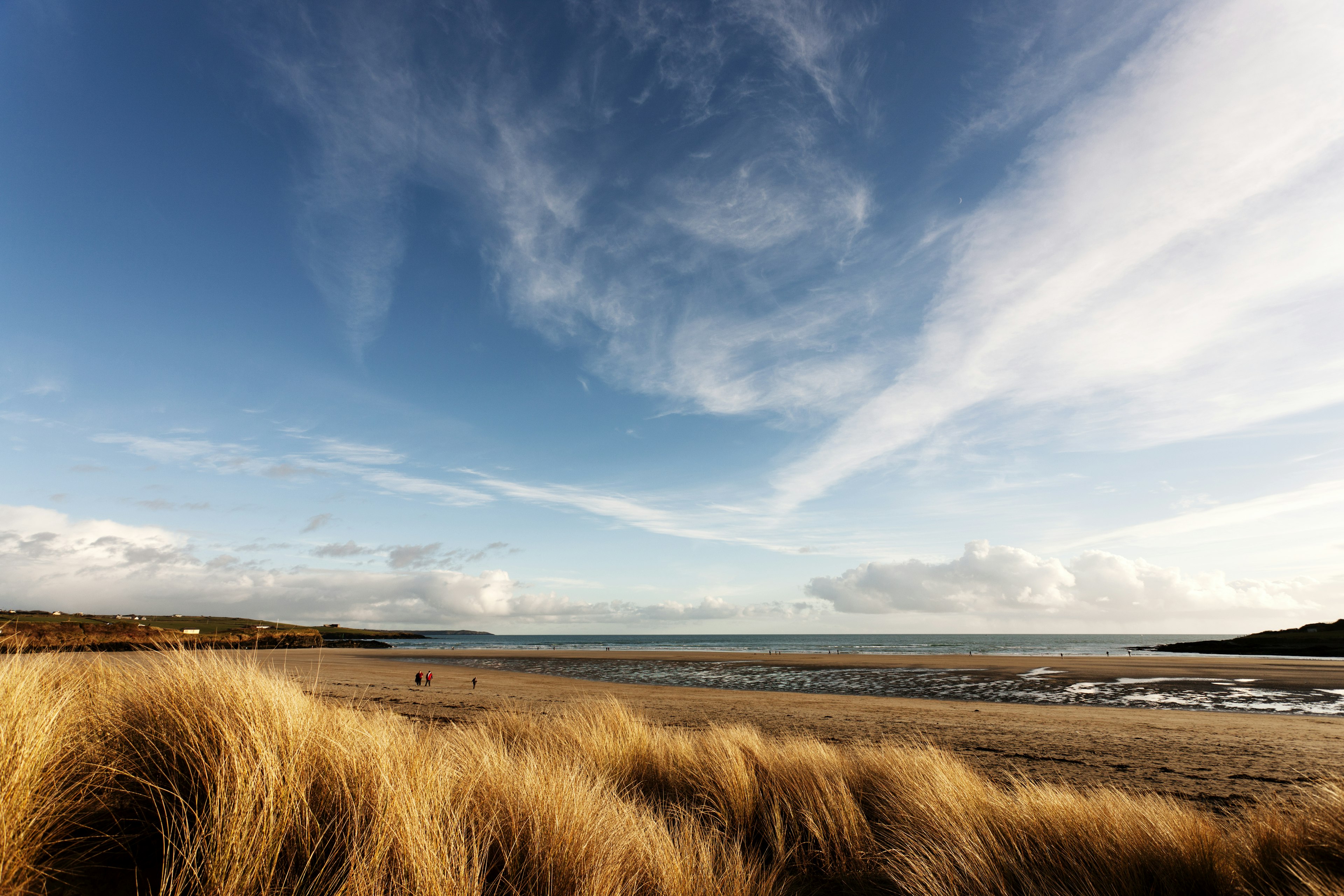 People walk along a beach on a sunny winter's day.