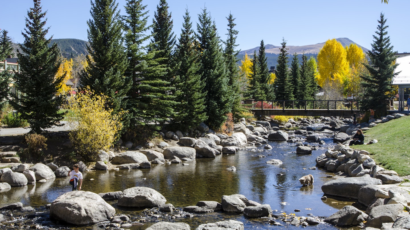 Breckenridge, Colorado, USA - October 12, 2015: Residents of Breckenridge enjoy a spectacular Fall afternoon by the Blue River in the Blue River Plaza and Riverwalk located in the town of Breckenridge, Colorado which was created in November 1859 by General George E. Spencer. The Blue River flows through a riverfront park created as a revitalization project by the town of Breckenridge. The historic Town of Breckenridge is the most populous municipality of Summit County, Colorado, United States. The town is located at the base of the Tenmile Range. Summer in Breckenridge attracts outdoor enthusiasts with hiking trails, wildflowers, fly-fishing in the Blue River, mountain biking, nearby Lake Dillon for boating, white water rafting, alpine slides, and several shops up and down Main Street.