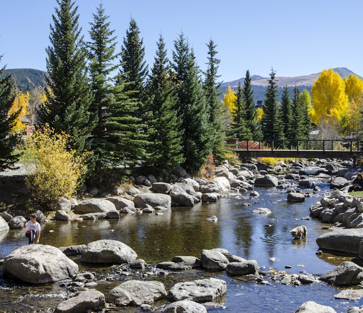 Breckenridge, Colorado, USA - October 12, 2015: Residents of Breckenridge enjoy a spectacular Fall afternoon by the Blue River in the Blue River Plaza and Riverwalk located in the town of Breckenridge, Colorado which was created in November 1859 by General George E. Spencer. The Blue River flows through a riverfront park created as a revitalization project by the town of Breckenridge. The historic Town of Breckenridge is the most populous municipality of Summit County, Colorado, United States. The town is located at the base of the Tenmile Range. Summer in Breckenridge attracts outdoor enthusiasts with hiking trails, wildflowers, fly-fishing in the Blue River, mountain biking, nearby Lake Dillon for boating, white water rafting, alpine slides, and several shops up and down Main Street.