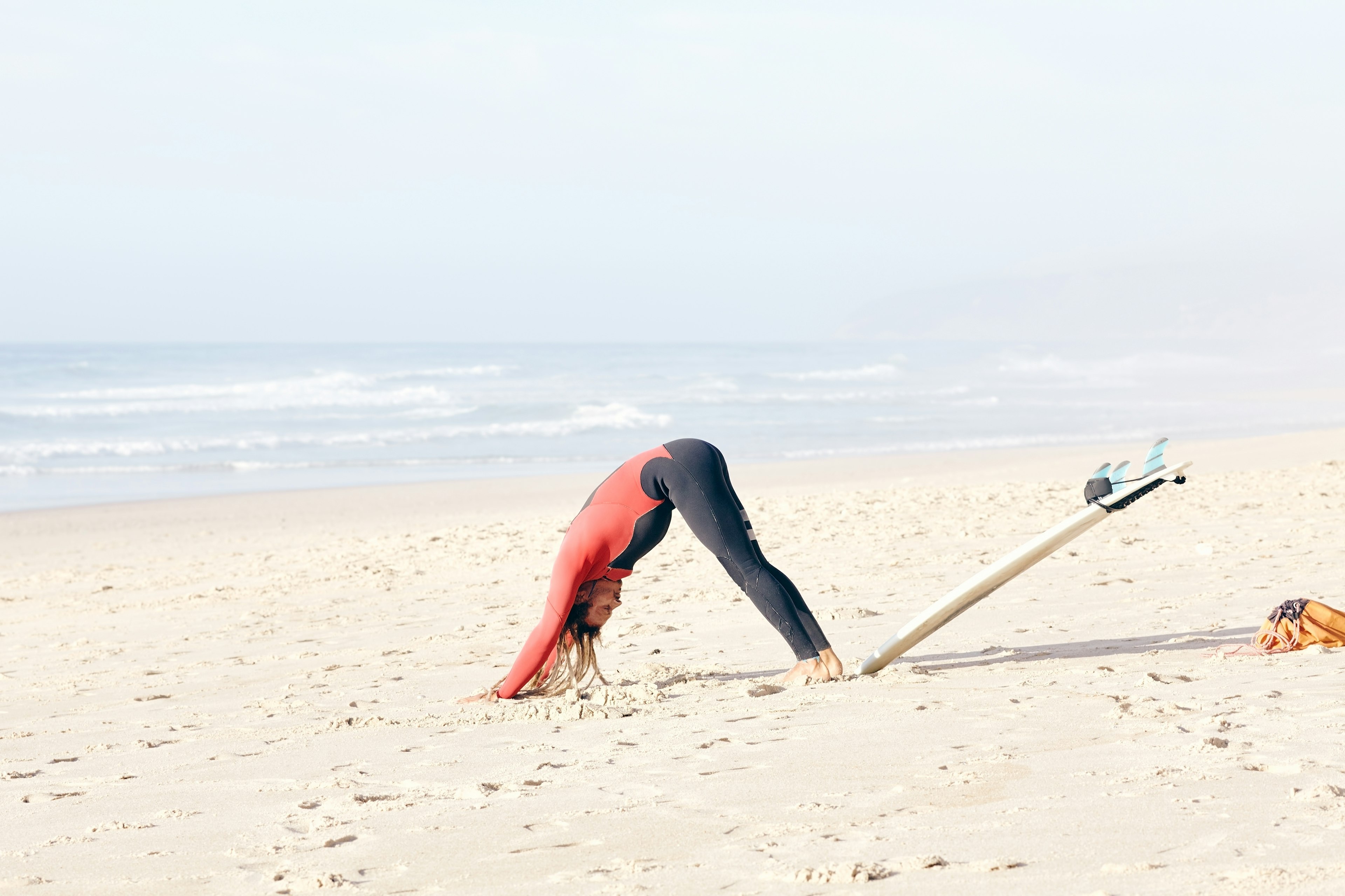 Young male surfer doing yoga pose on beach