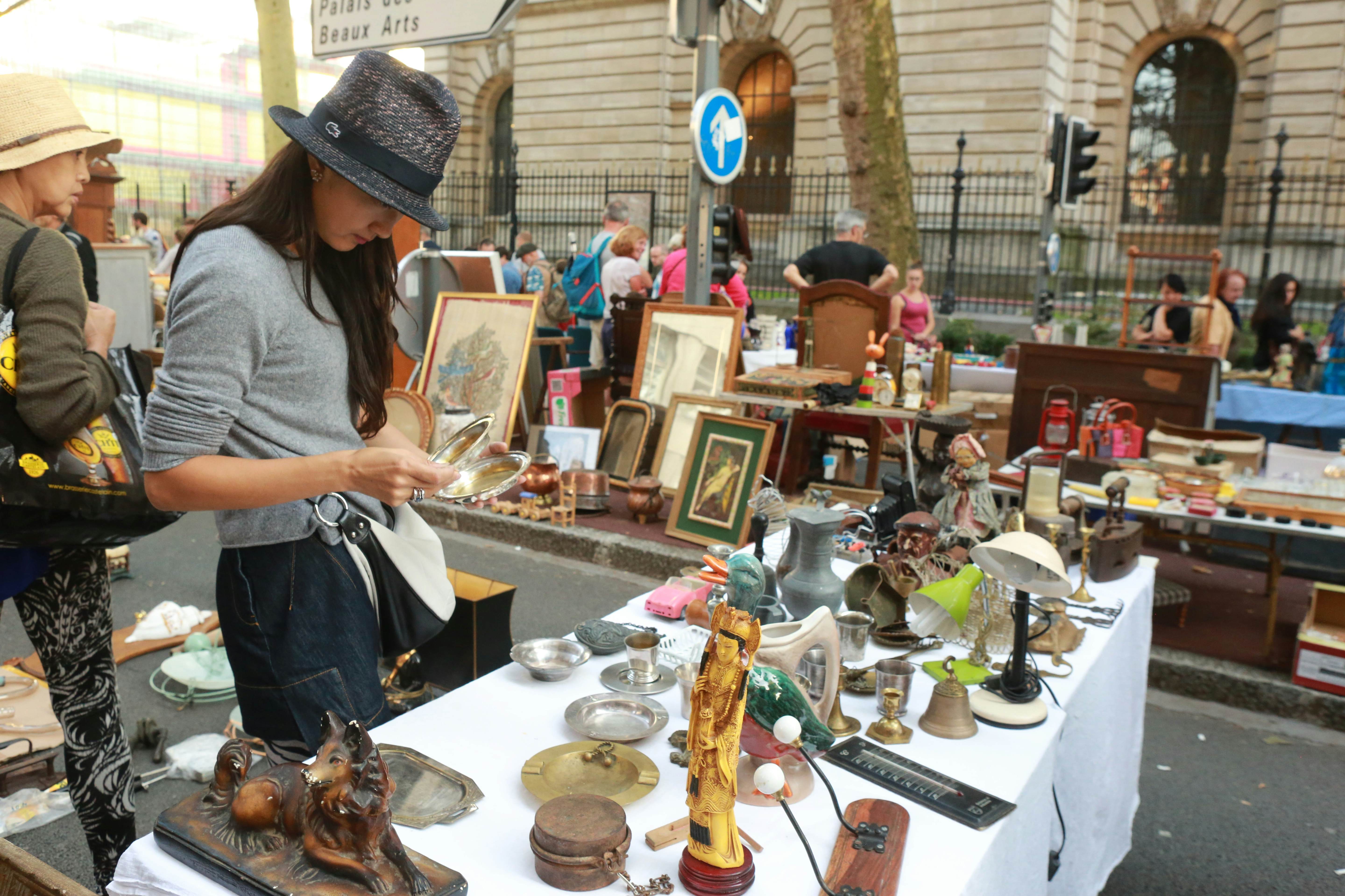 A woman sorts through a collection of items at a flea market stall