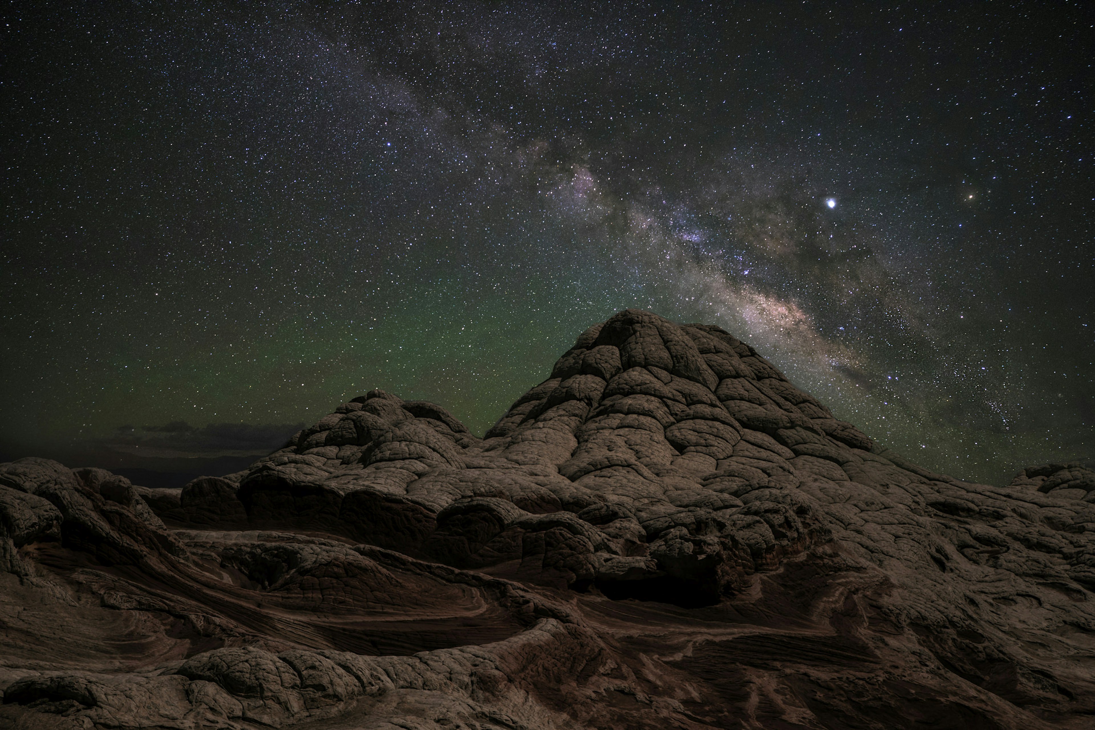 The White Pocket sandstone plateau at night with the Milky Way.