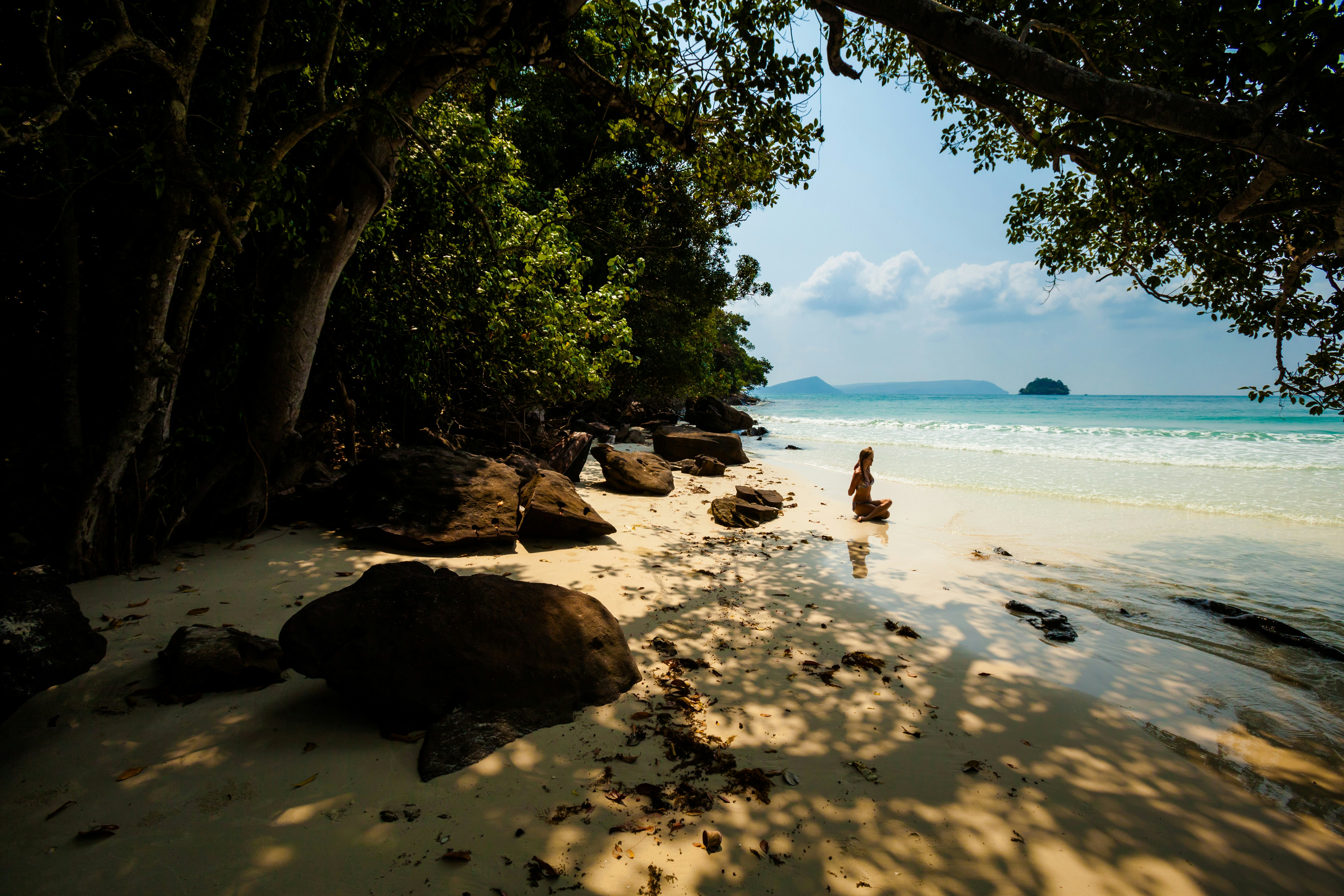 Woman sitting on tropical beach doing yoga