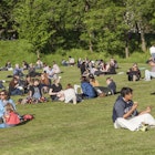 Crowd of people relaxing on the grass at Kelvingrove Park during the Glasgow Mela.