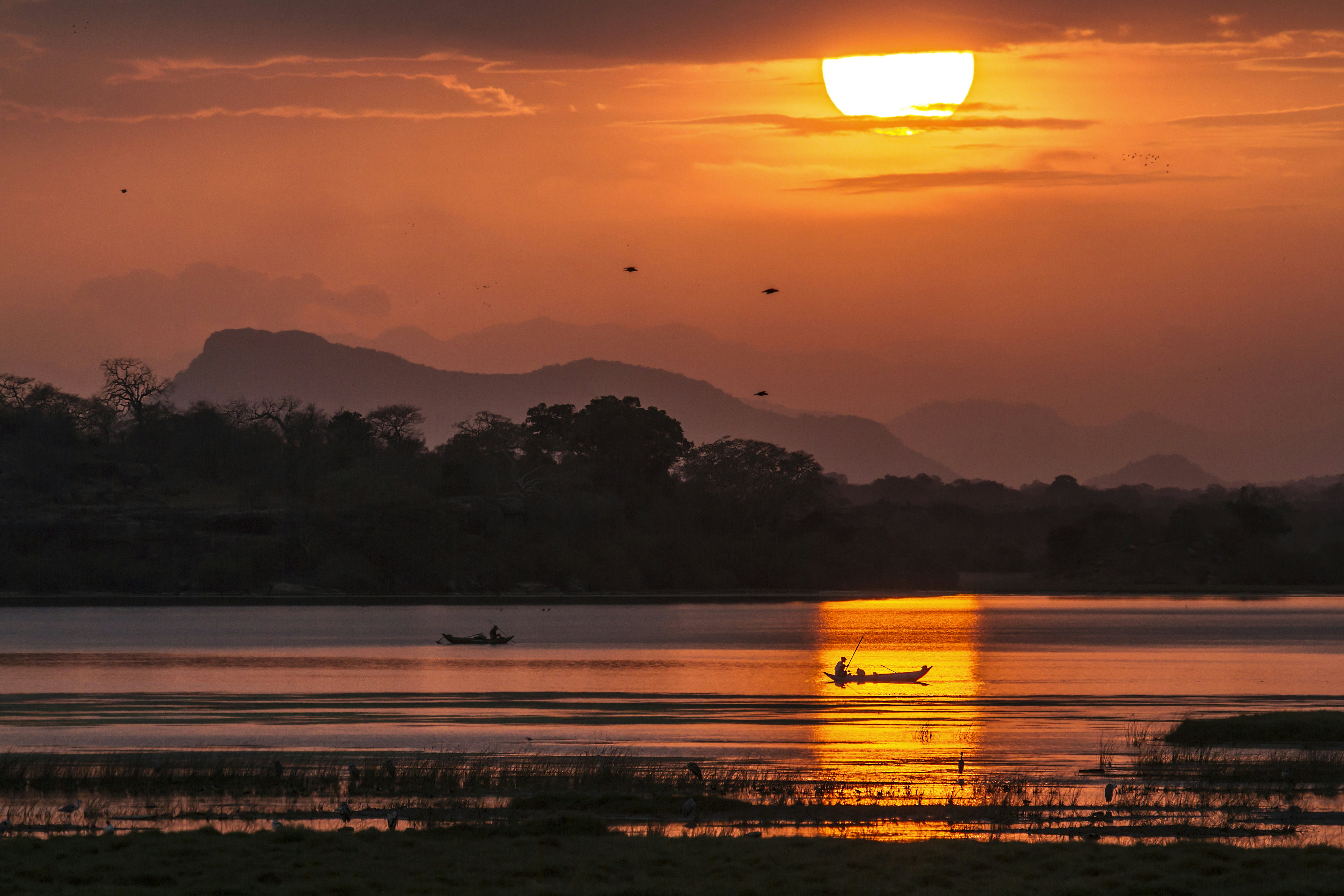 Fisherman in boats in Arugam bay lagoon during sunset.