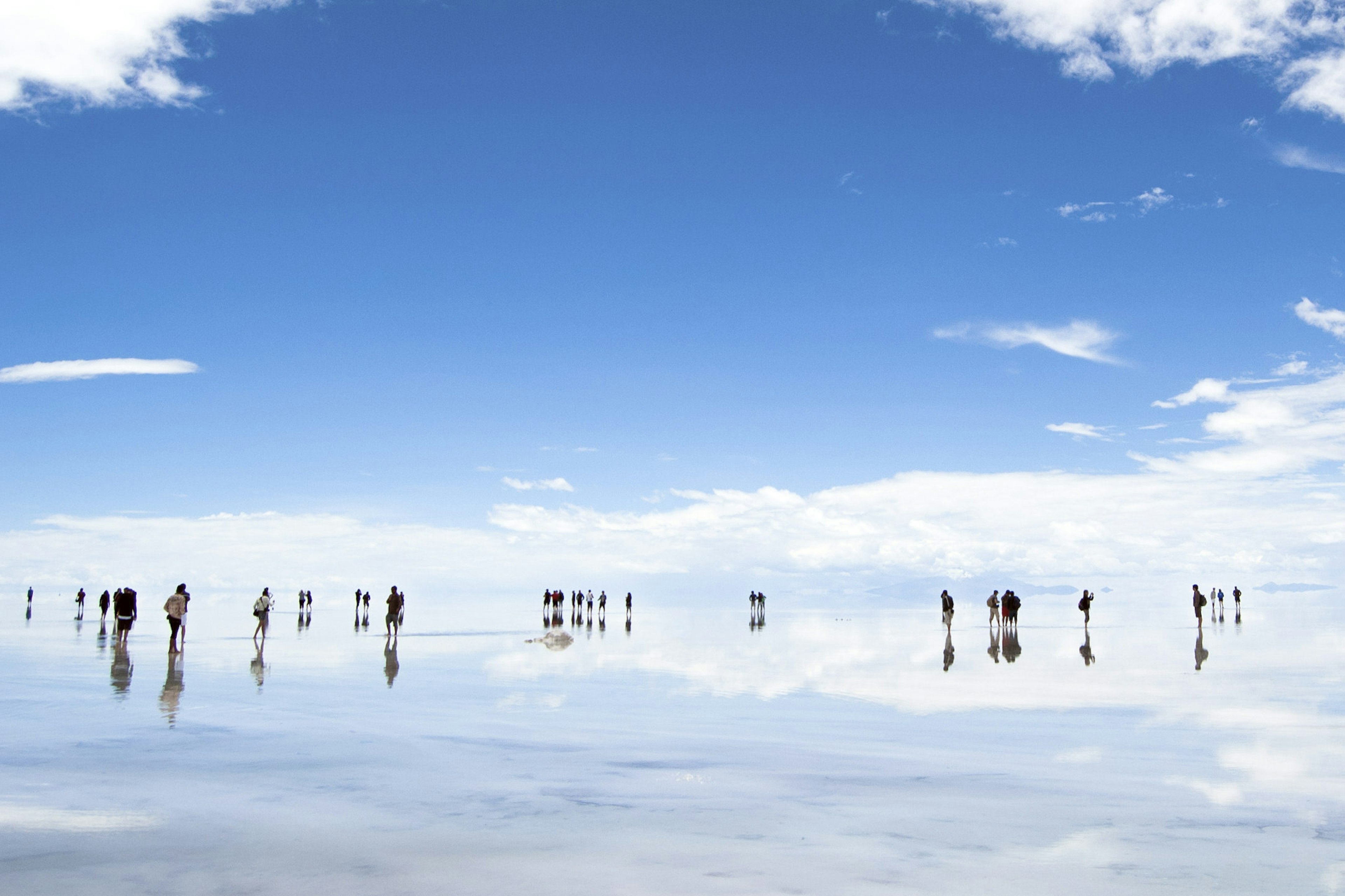 Visitors stand in shallow water at the salt flats of Salar de Uyuni..