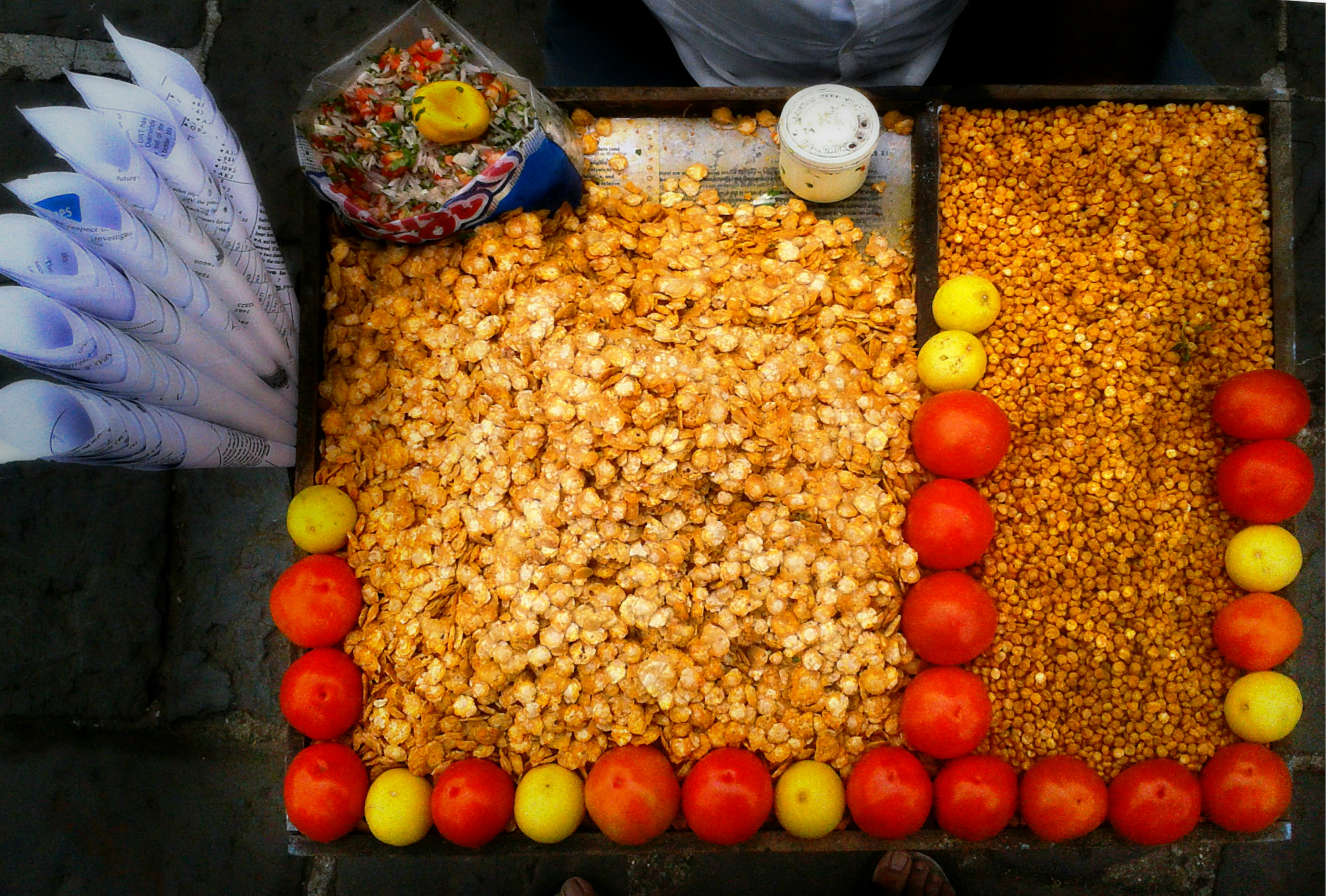 Food basket of 'Chana jor garam' on a Mumbai pavement market. Chana Jor Garam is a tasty Indian traditional snack made out of black gram eaten with assortment of few drops of lemon juice, onion and tomato slices.