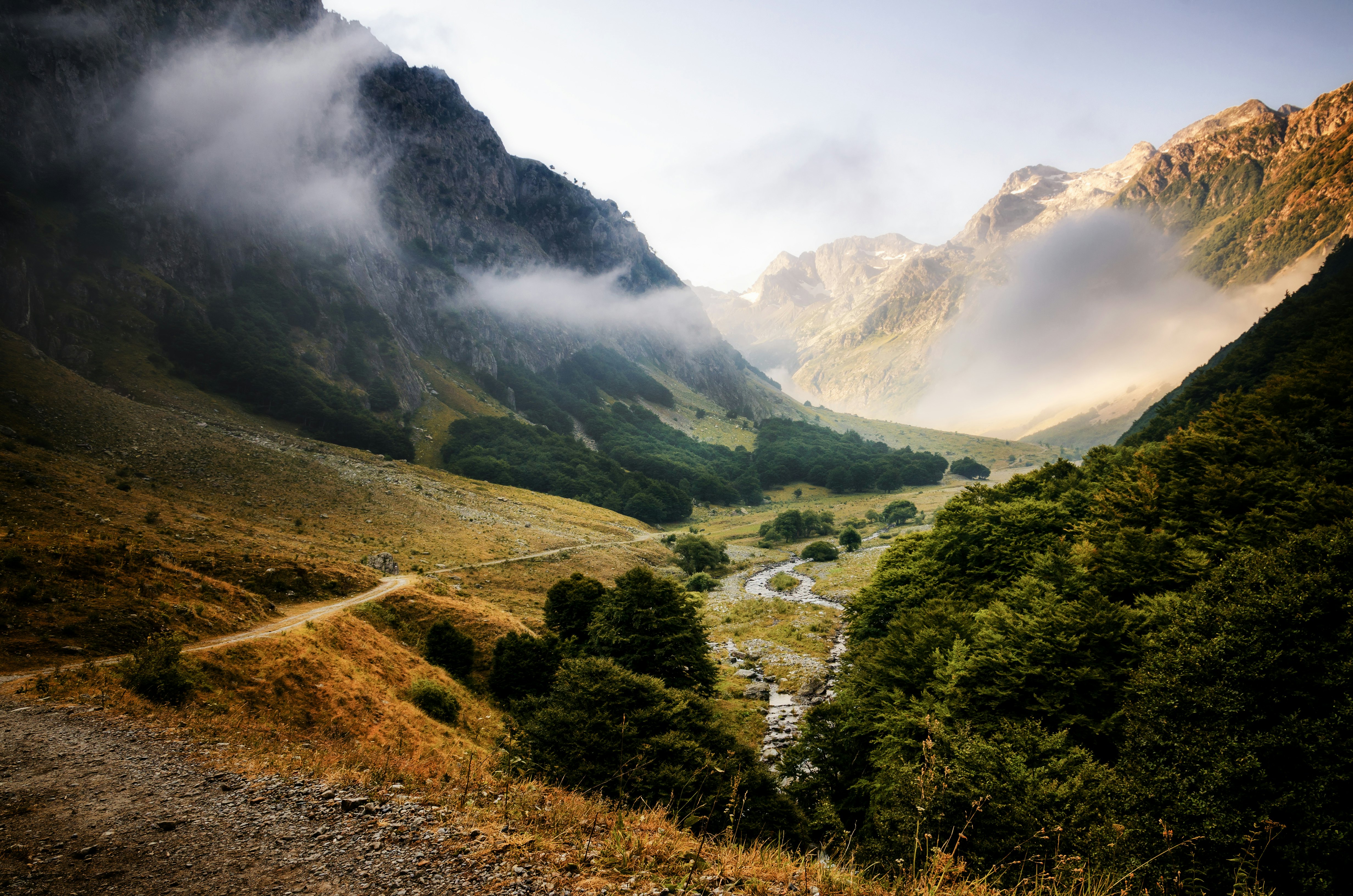 A rugged valley, wreathed with clouds and flanked by craggy mountains