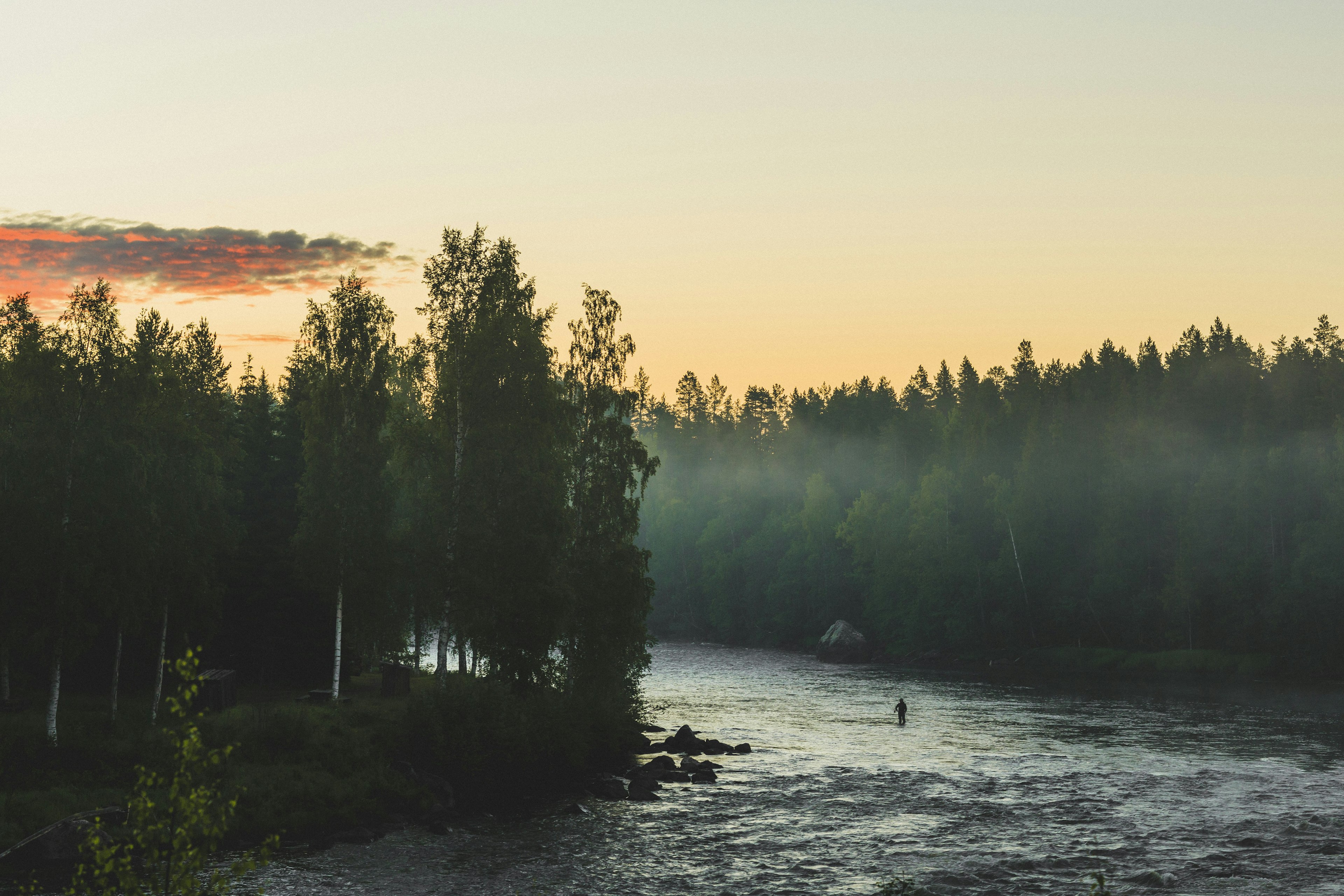 A solitary man fishes with a fly rod in a river in Sweden.