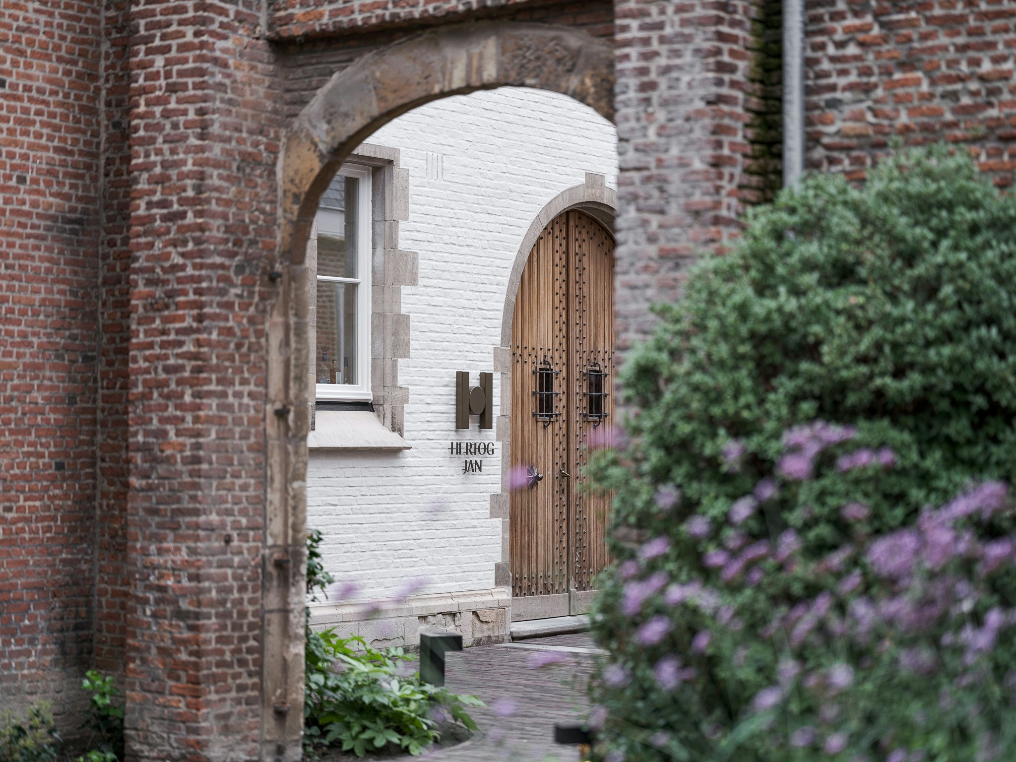 A door with the sign "Hertog Jan" within a red-brick archway