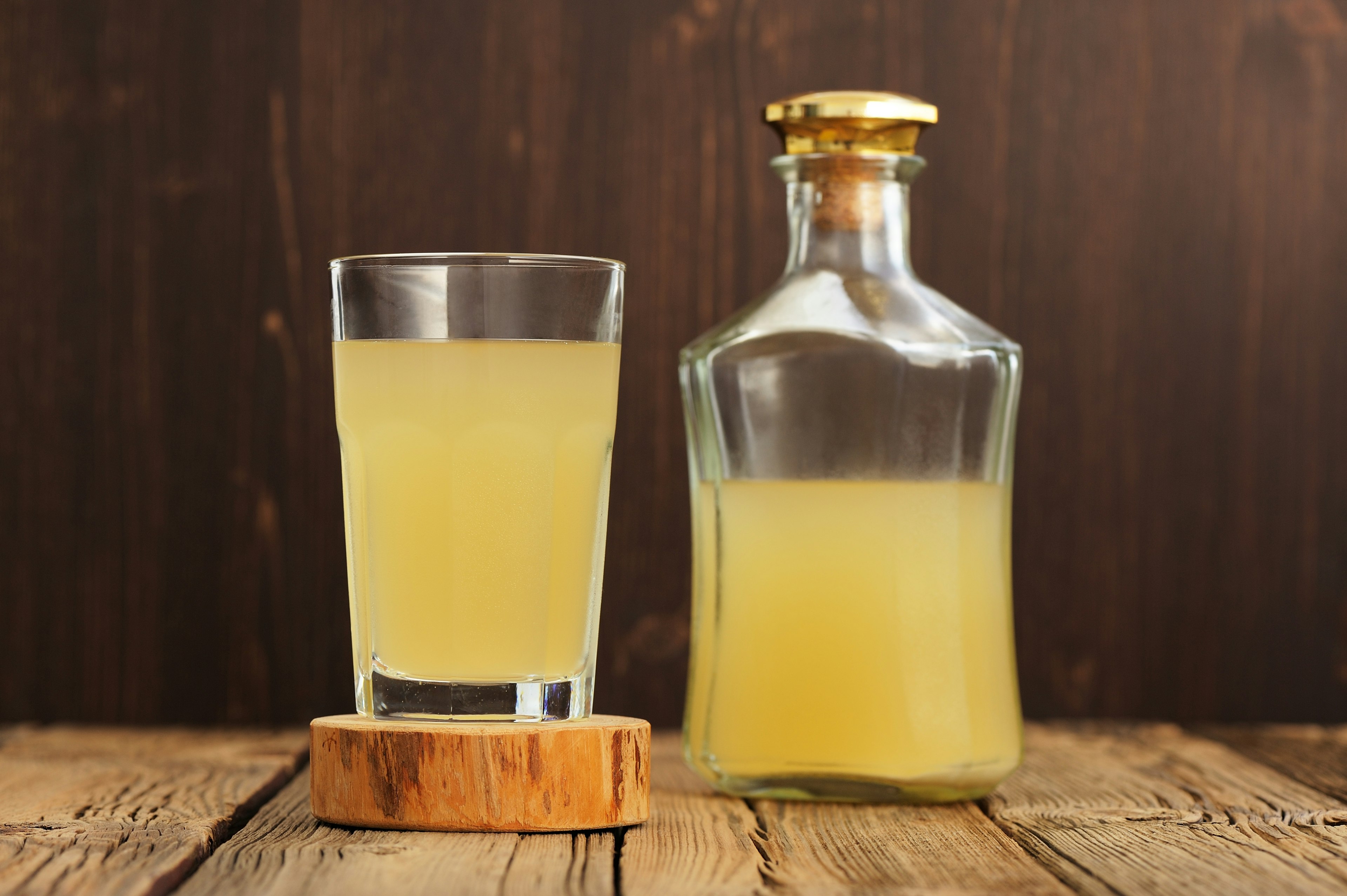 Russian cold rye beverage Kvass in glass and bottle on wooden table horizontal.