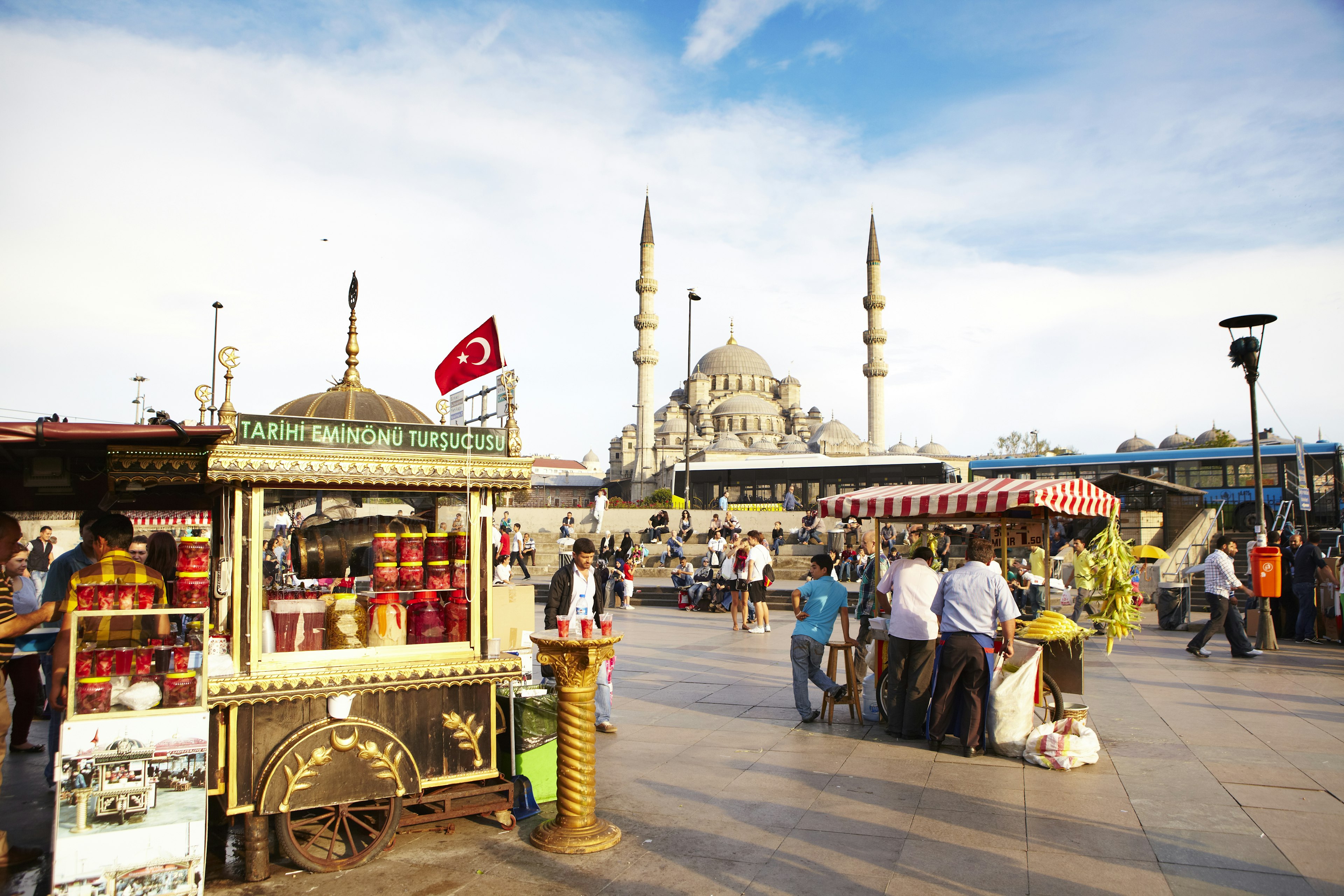 Food carts in a public square with the a large mosque and two tall minarets