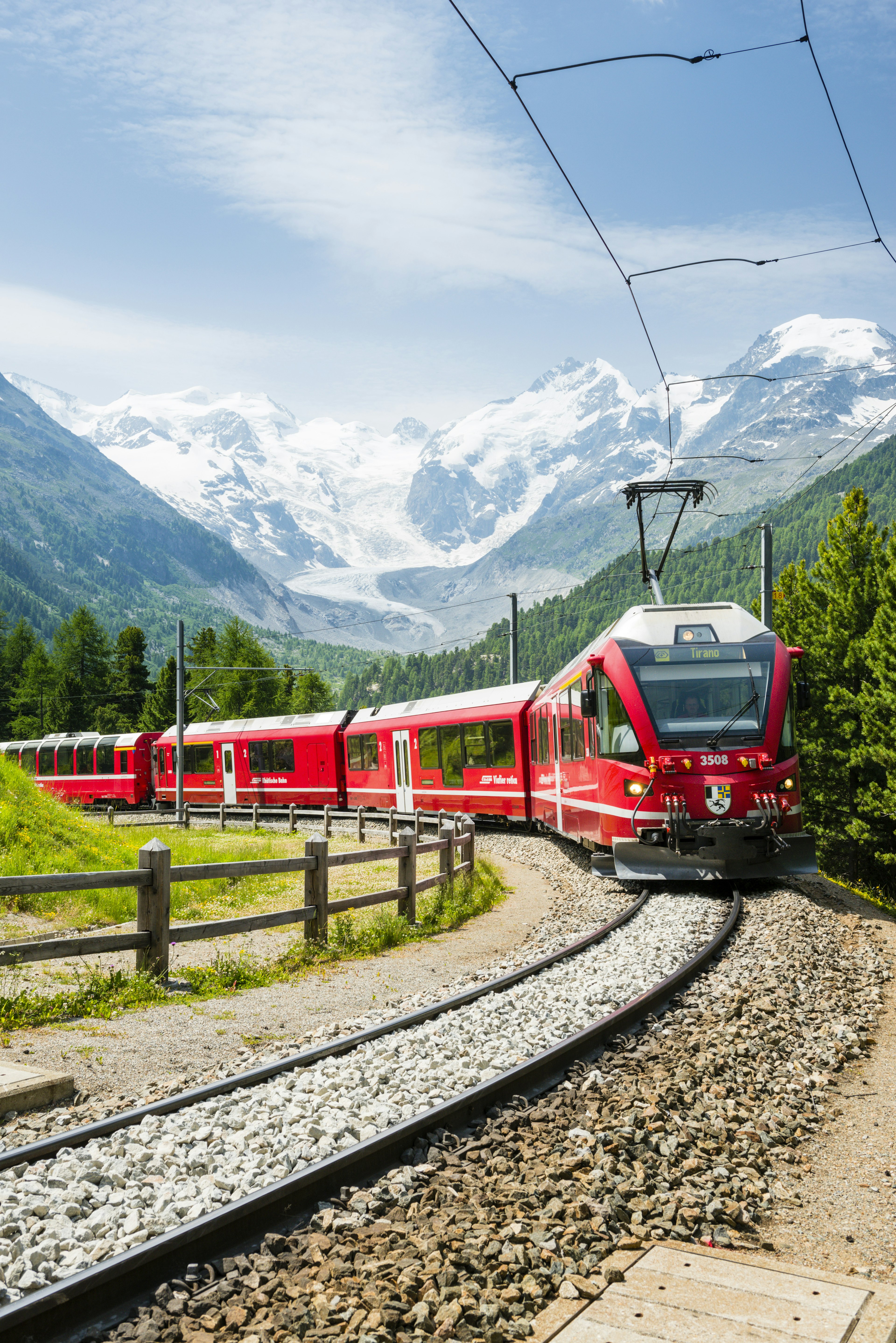 The Bernina Express train follows a curving track with mountains all around it