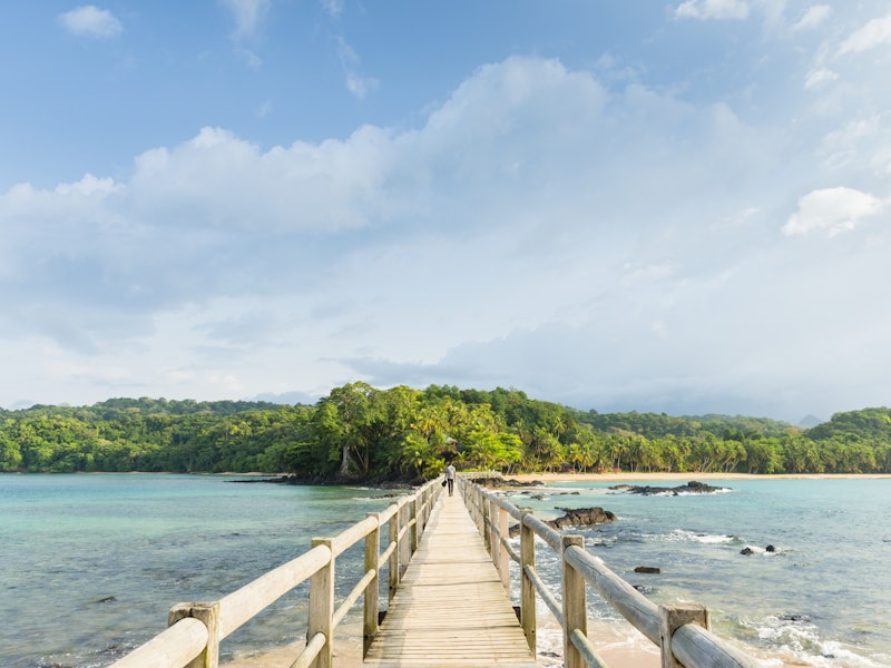 A walking bridge from Bom Bom Resort on Principe Island with green trees in the distance.