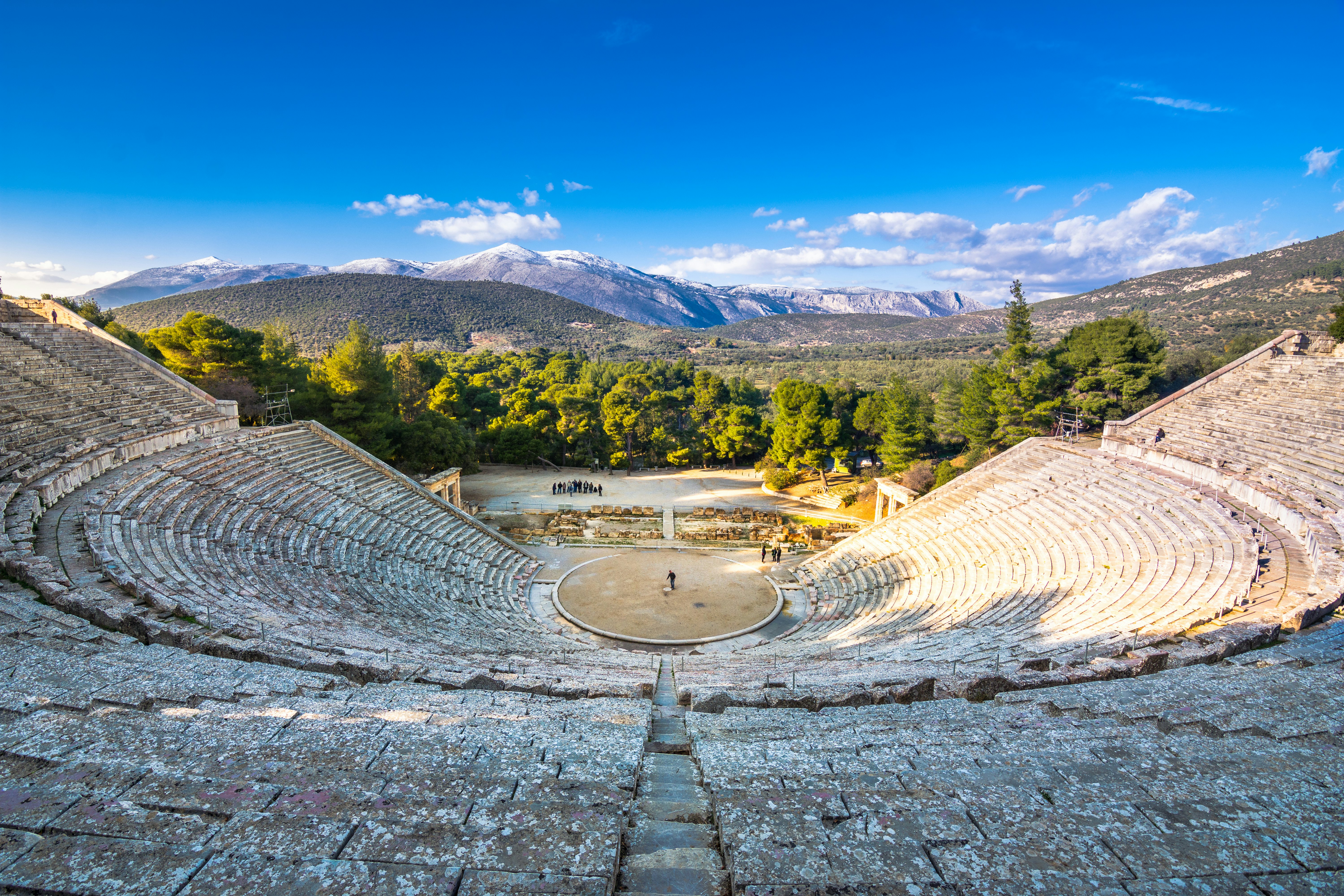 A view of an ancient amphitheater with hills in the background