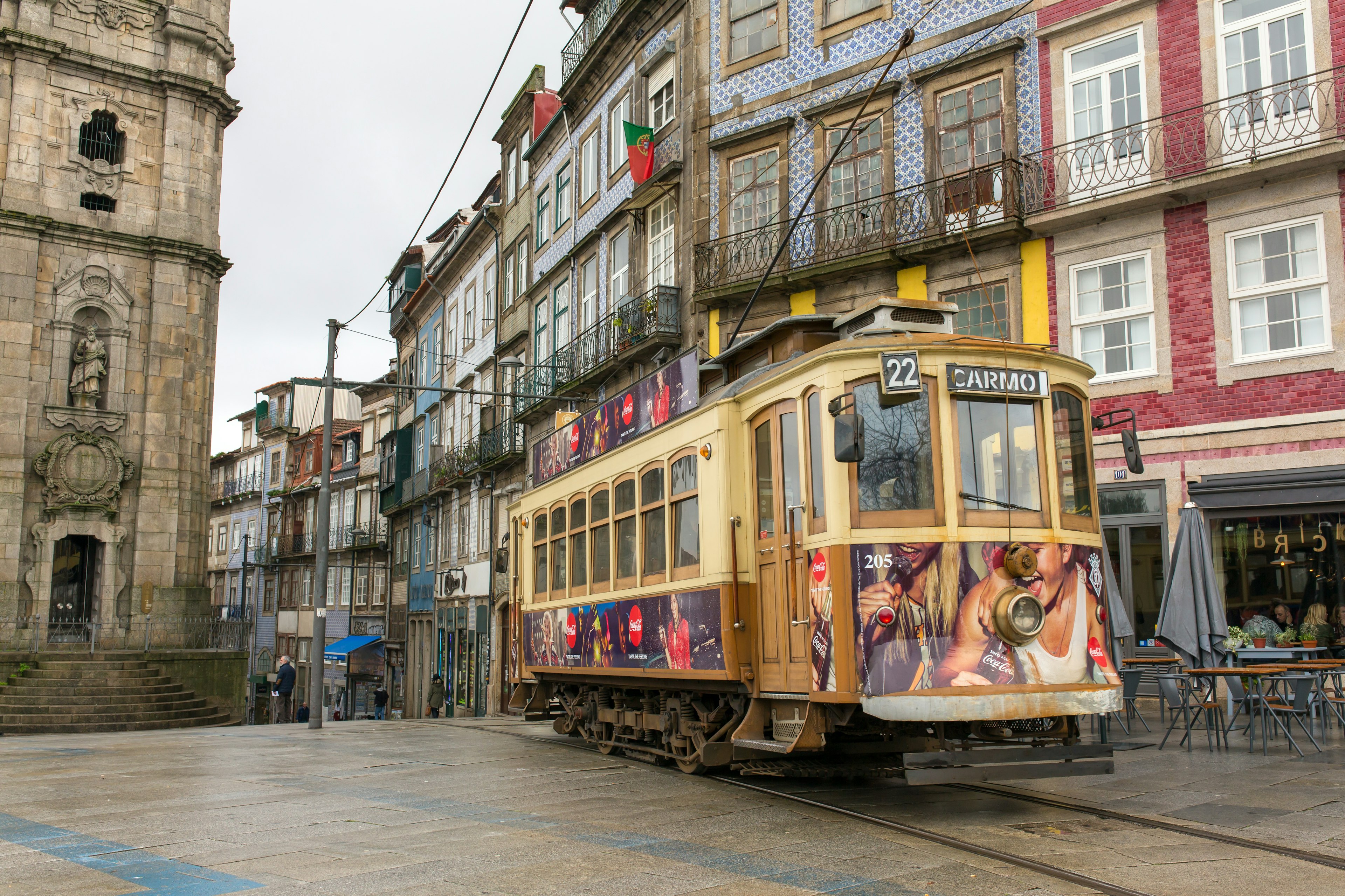 A tram covered in advertisements chugs along a track through a historic city center