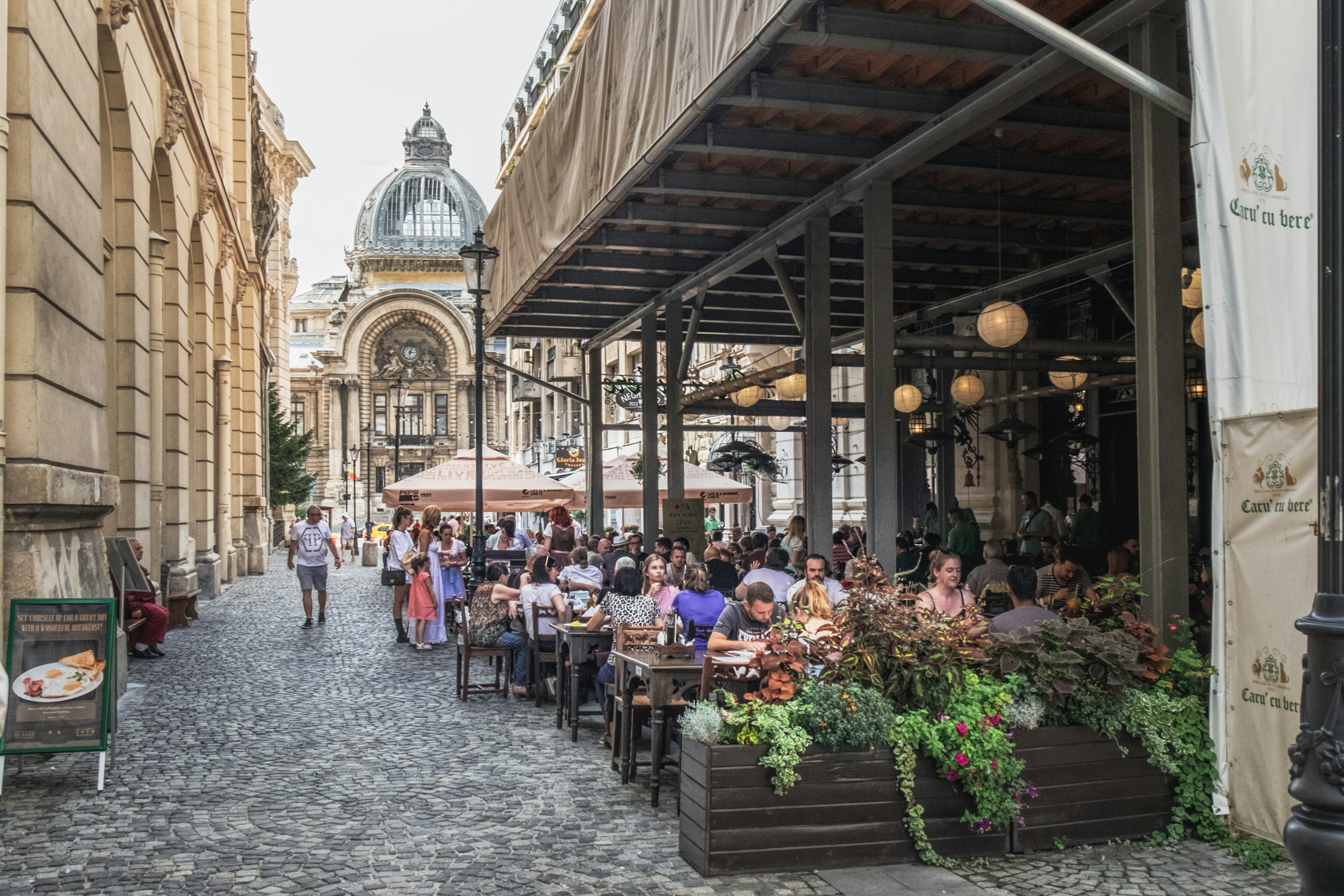 People at tables at an outdoor cafe on a cobbled, pedestrianized street in Bucharest, Romania