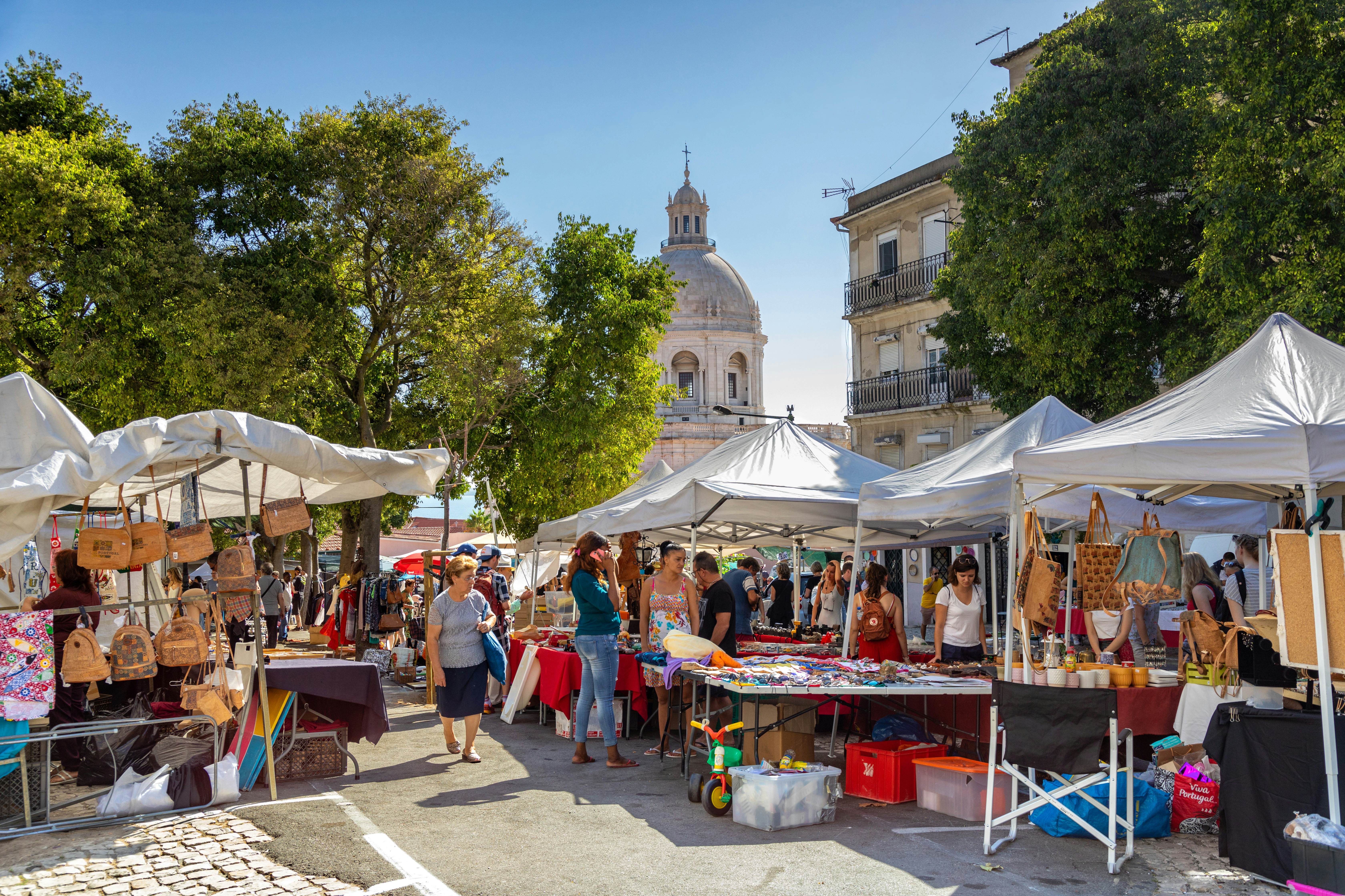 People browse stalls at an outdoor flea market on a sunny day