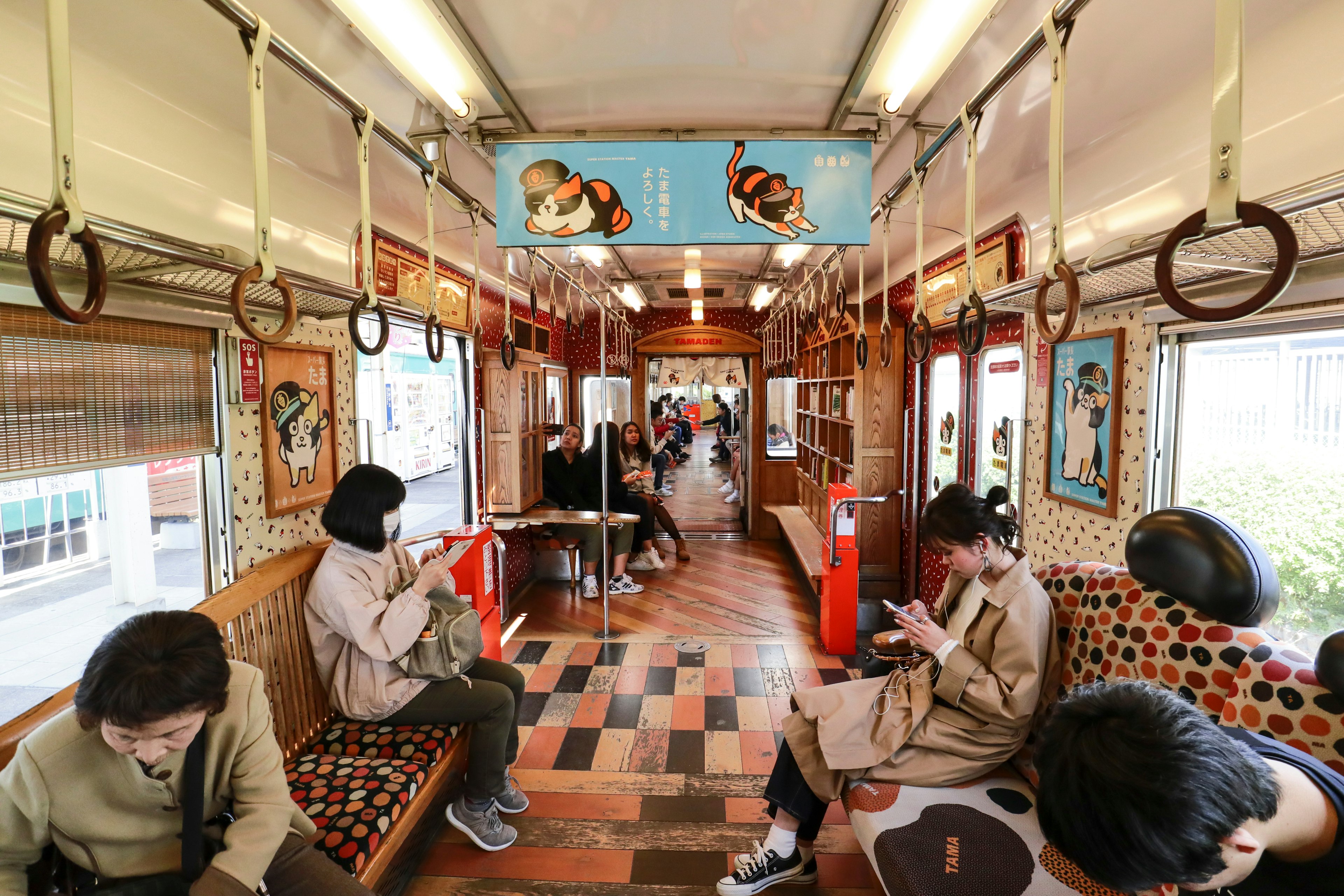 People sat on bench-like seats lining a train carriage in Japan all playing on their cell phones