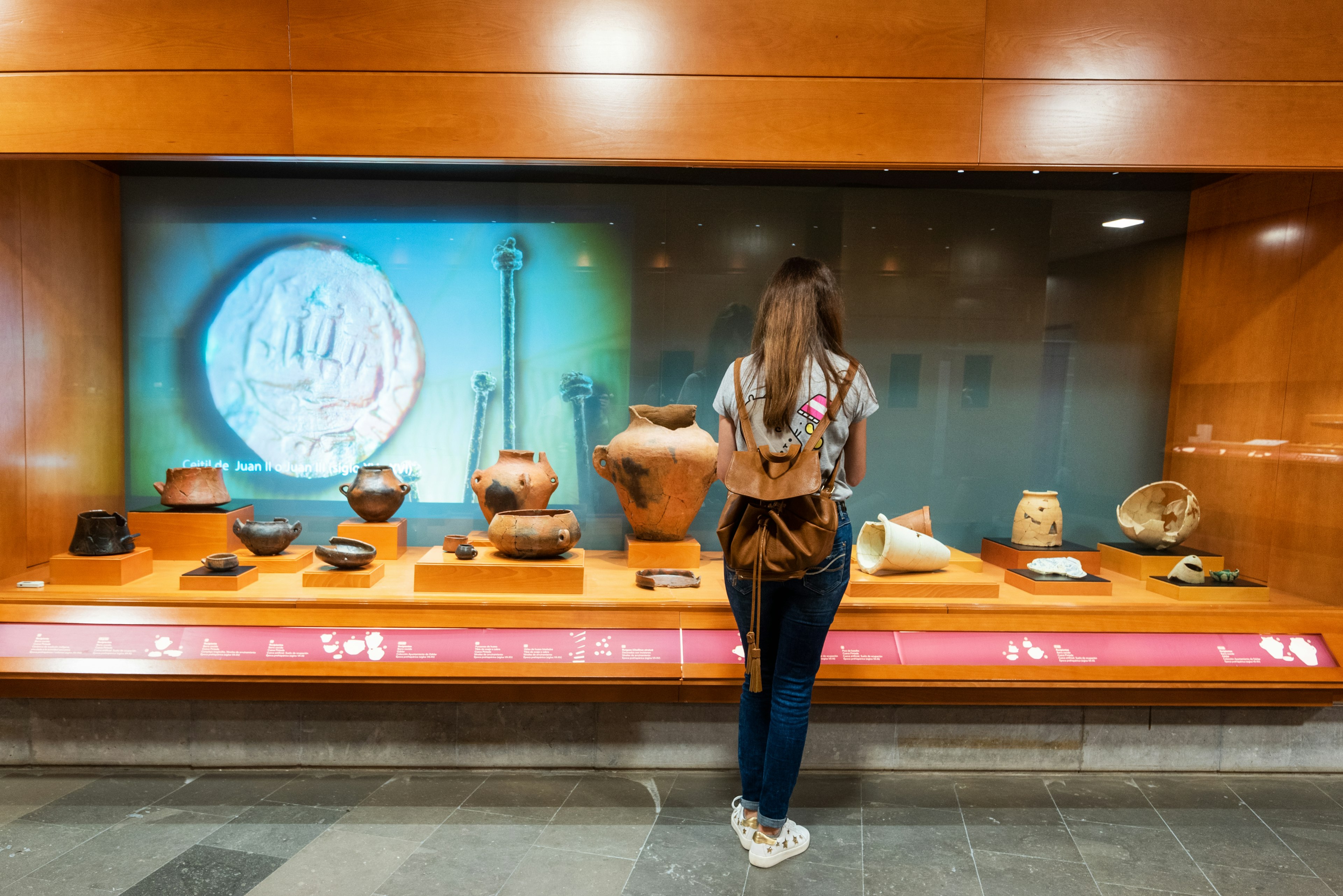 A woman looks at excavated pottery and other objects at the museum of the Cueva Pintada, Gran Canaria, Canary Islands, Spain