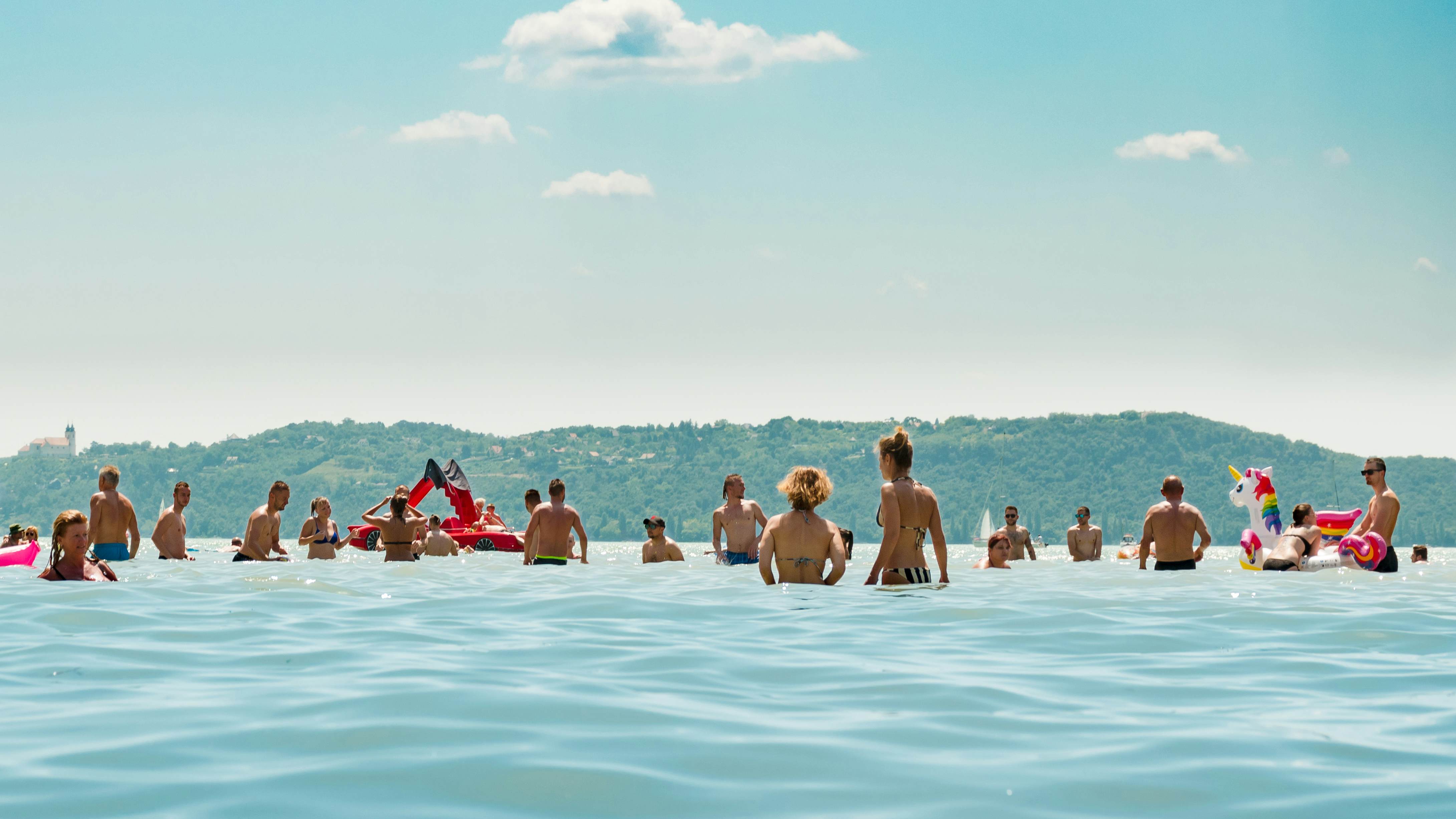 People are having fun, chilling, and swimming in the lake Balaton on a very hot summer day.