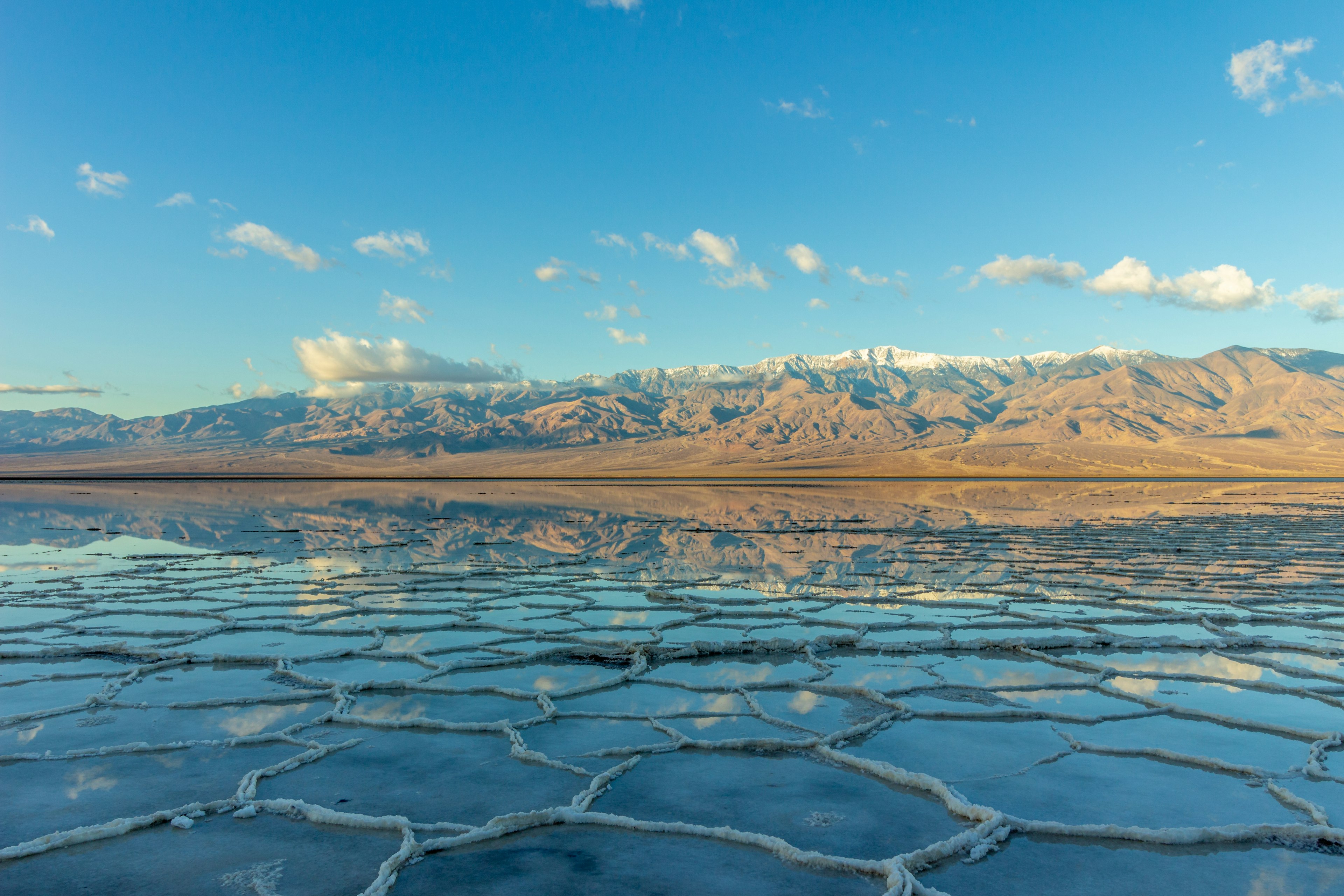 Salt flats with a layer of water reflecting the distant mountains like a lake