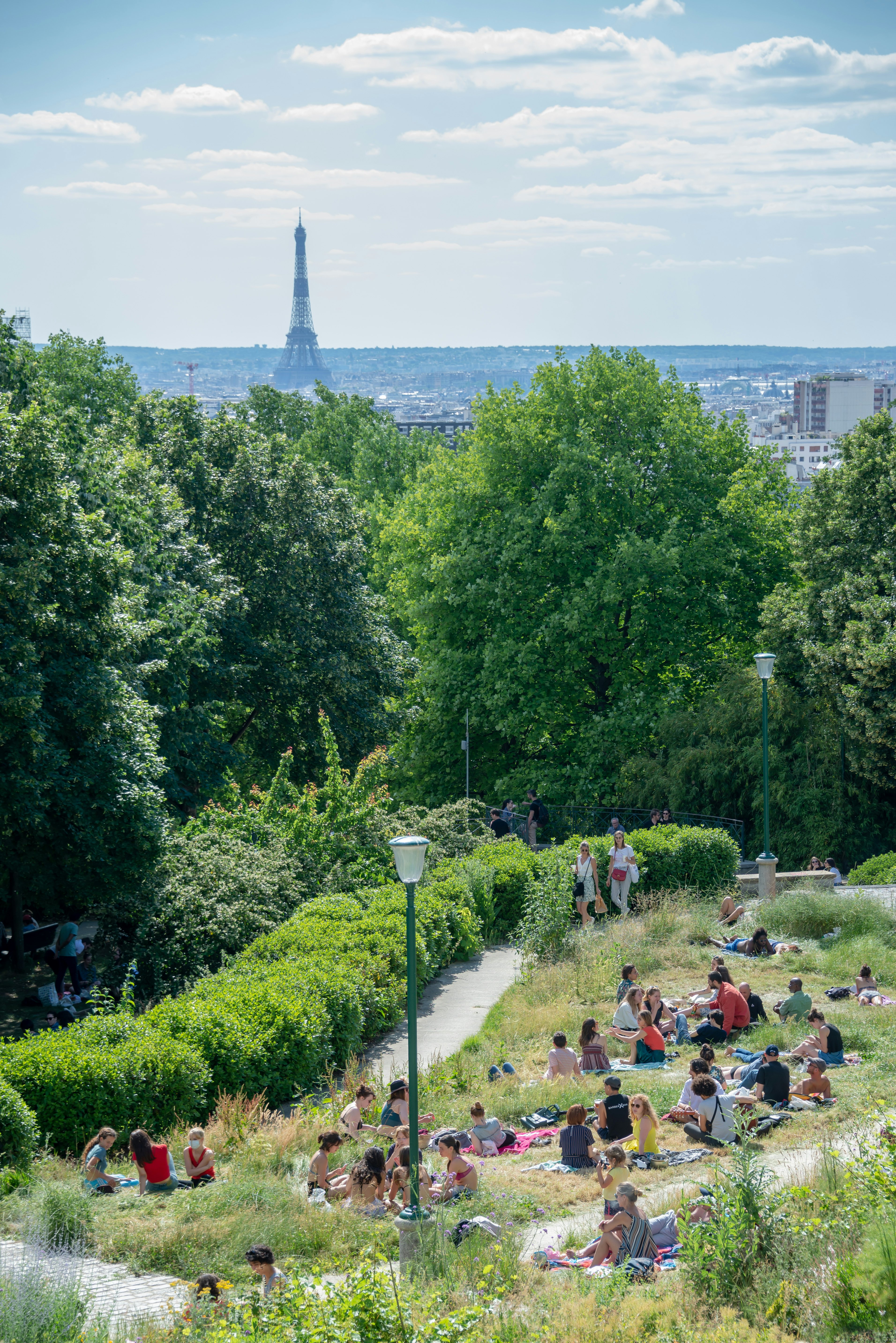 People in Parc de Belleville enjoying the view on the Eiffel tower during in sunny day