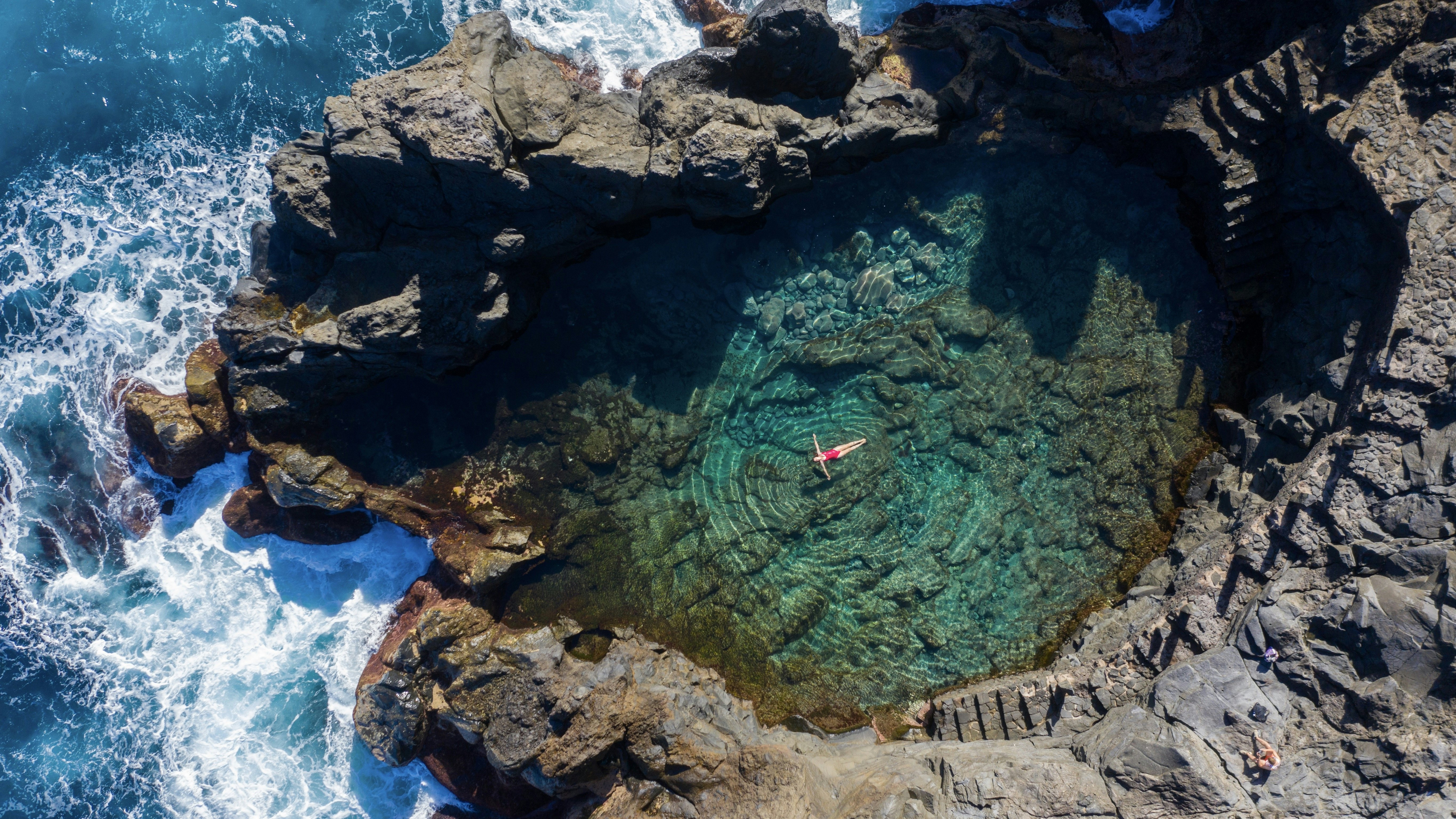 A woman floats in the water of a rock pool in Tenerife.