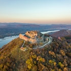 Visegrad, Hungary - Aerial panoramic drone view of the beautiful high castle of Visegrad on a moody autumn sunset. Danube Bend (Dunakanyar) and amazing golden sunset at background. License Type: media Download Time: 2023-02-22T22:33:49.000Z User: mvm_lonelyplanet Is Editorial: No purchase_order: