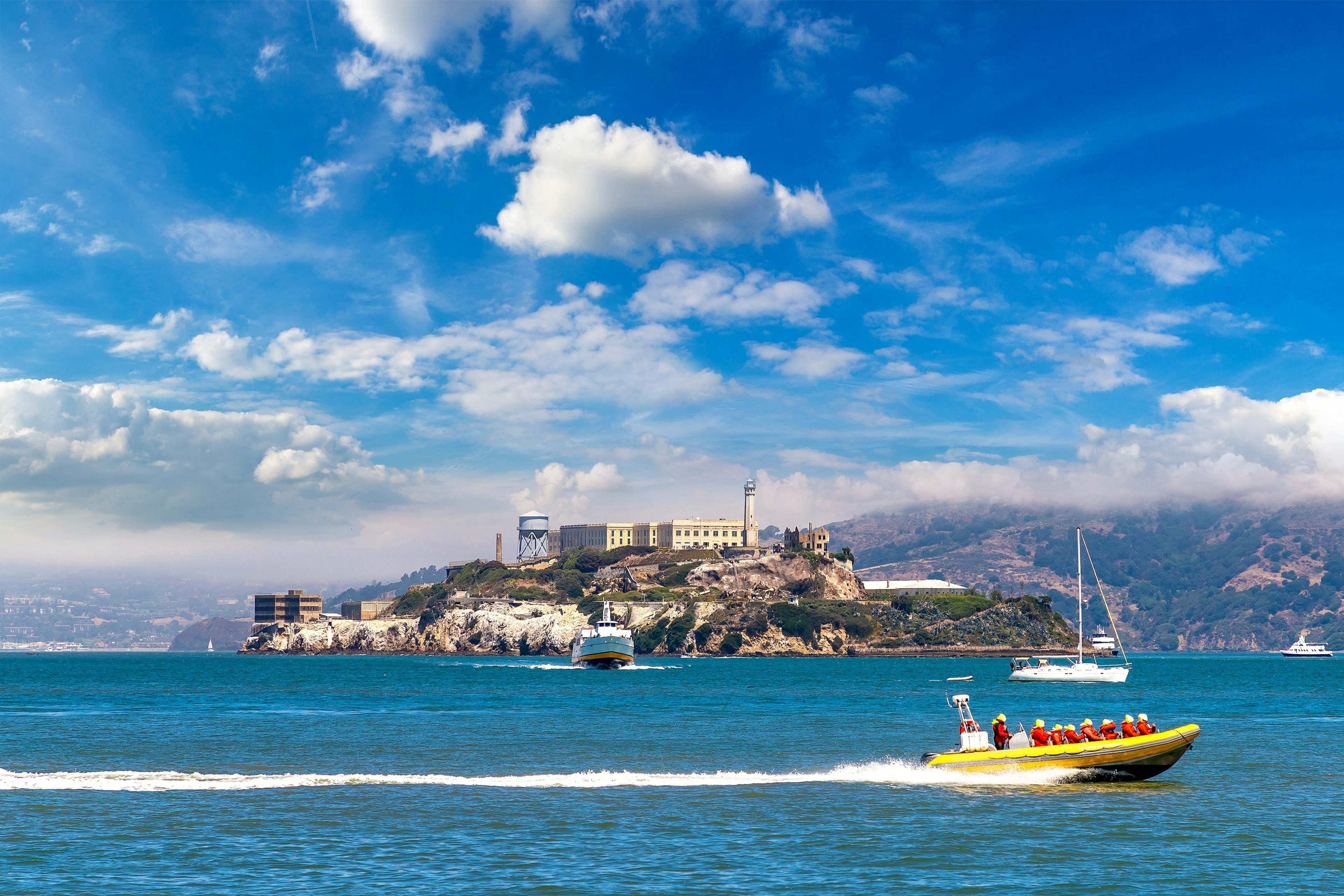 A tourist boat sails by an island with a large prison built on it