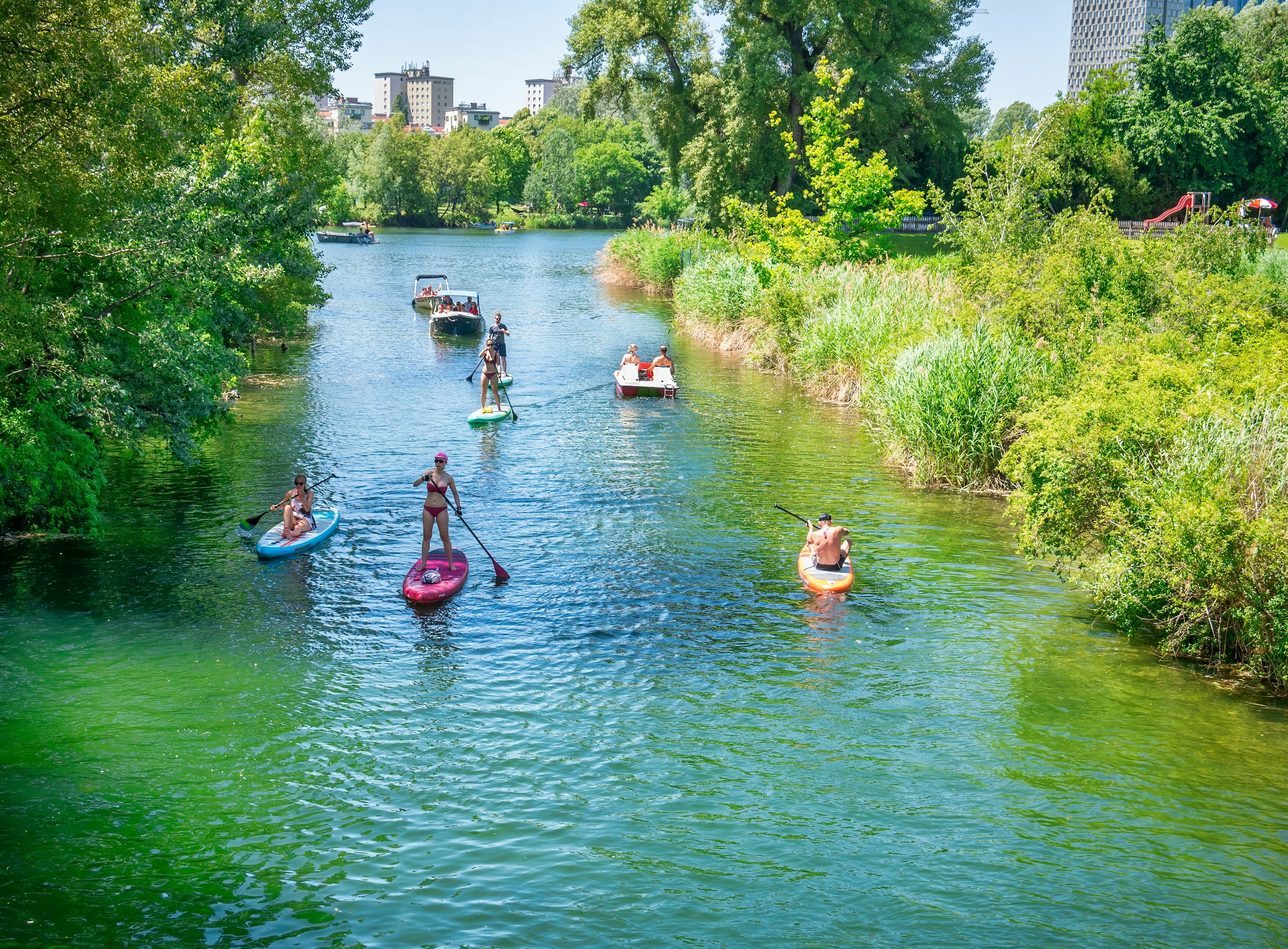 Vienna, Austria - June 2022: Summer landscape at the beach  with people paddling in kayaks and stand up boards in Kaiserwasser Alte Donau park ( Strandbad Gansehaufel)