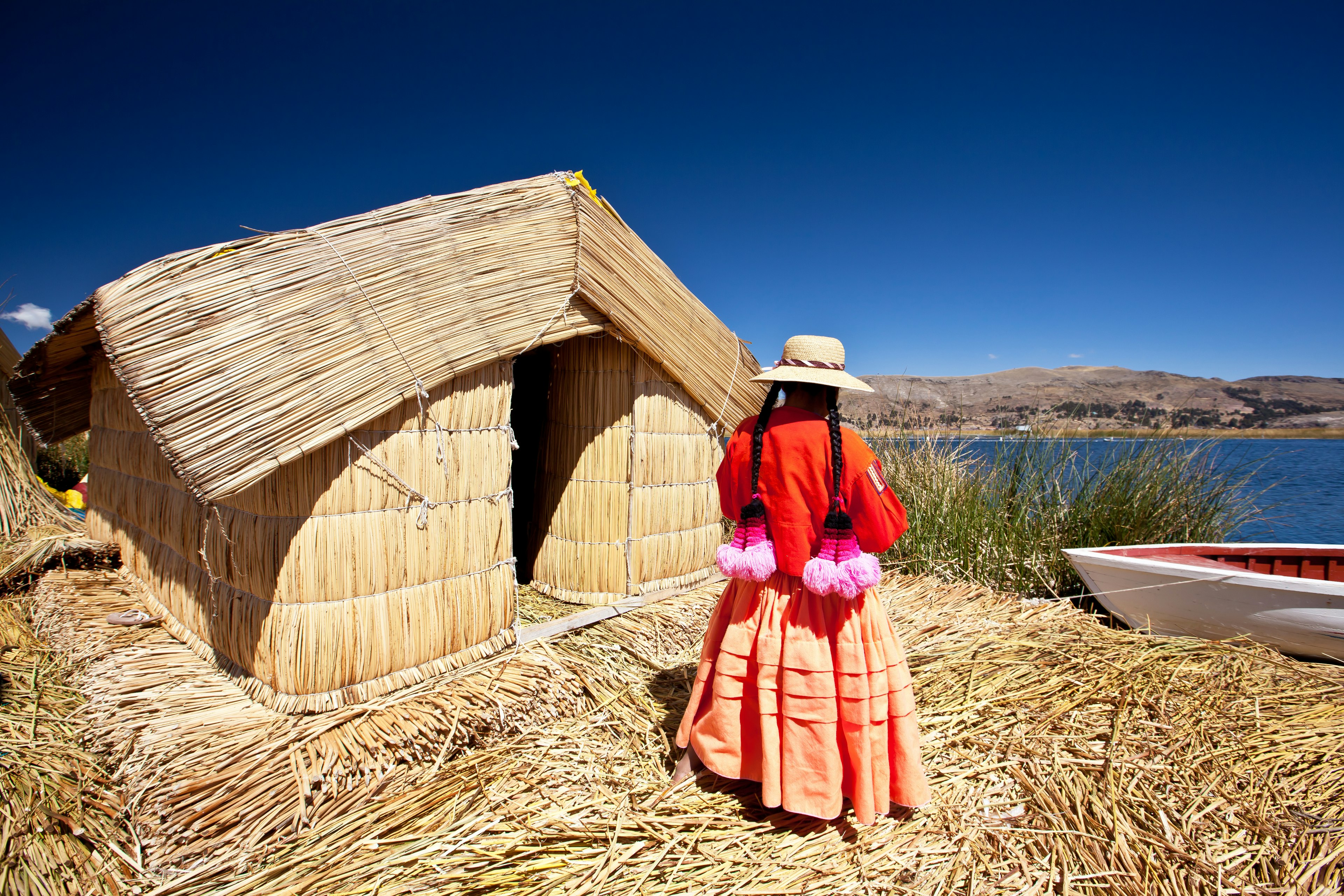 A woman stands outside a reed house on Lake Titikaka, Peru.