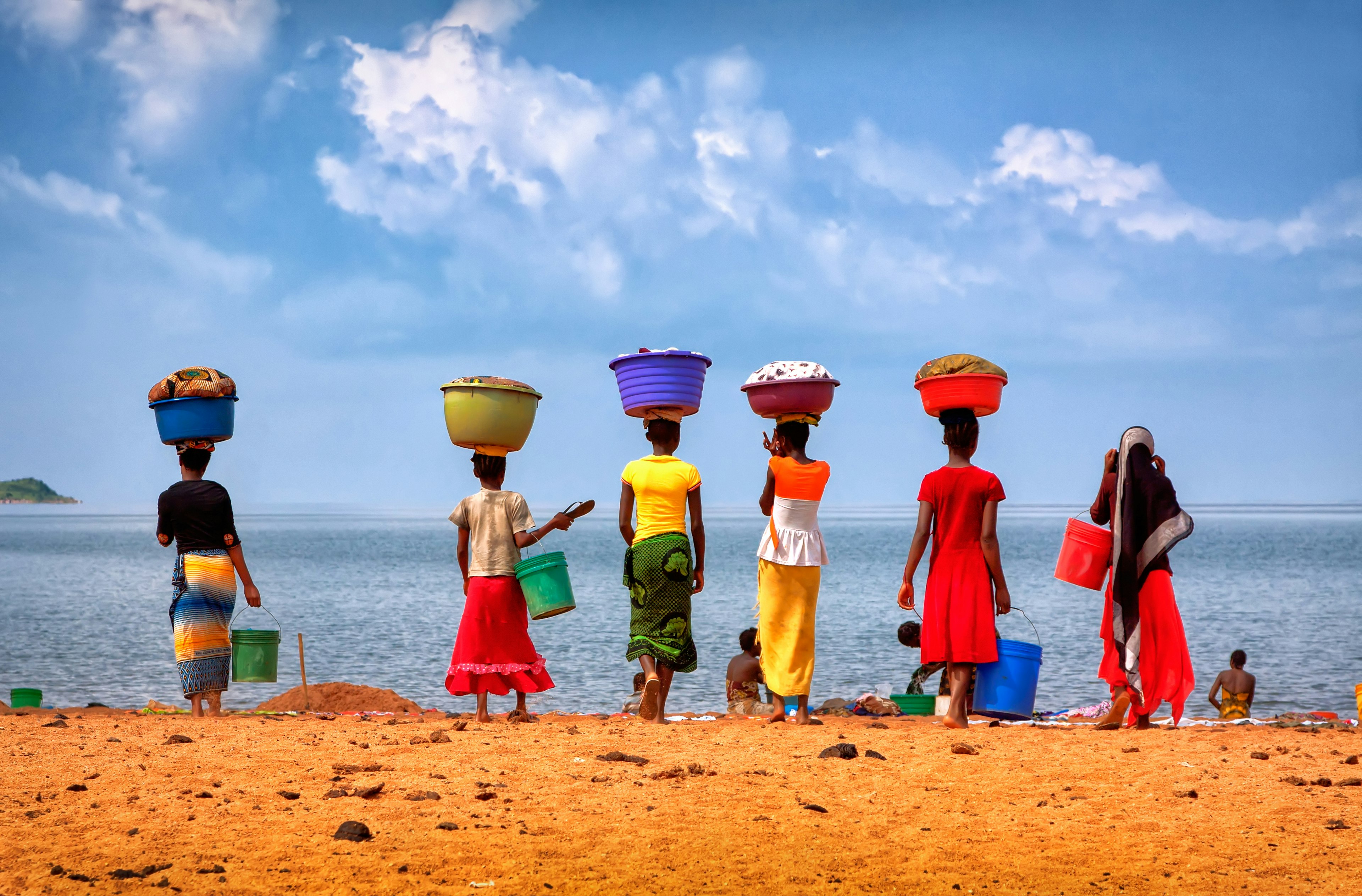 Women carrying laundry to wash in Lake Tanganyika, Tanzania.