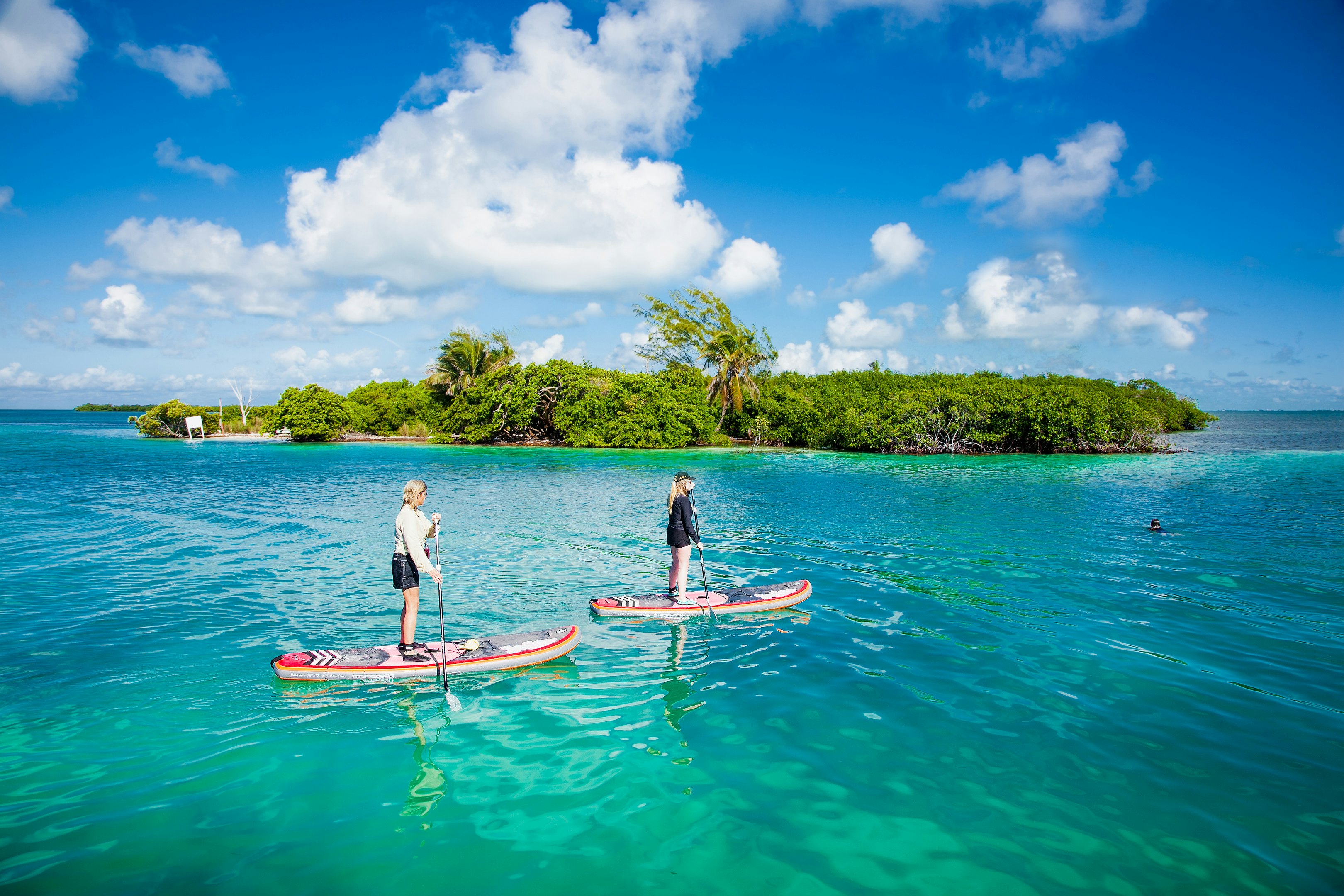 People paddleboard in the waters by Caye Caulker island