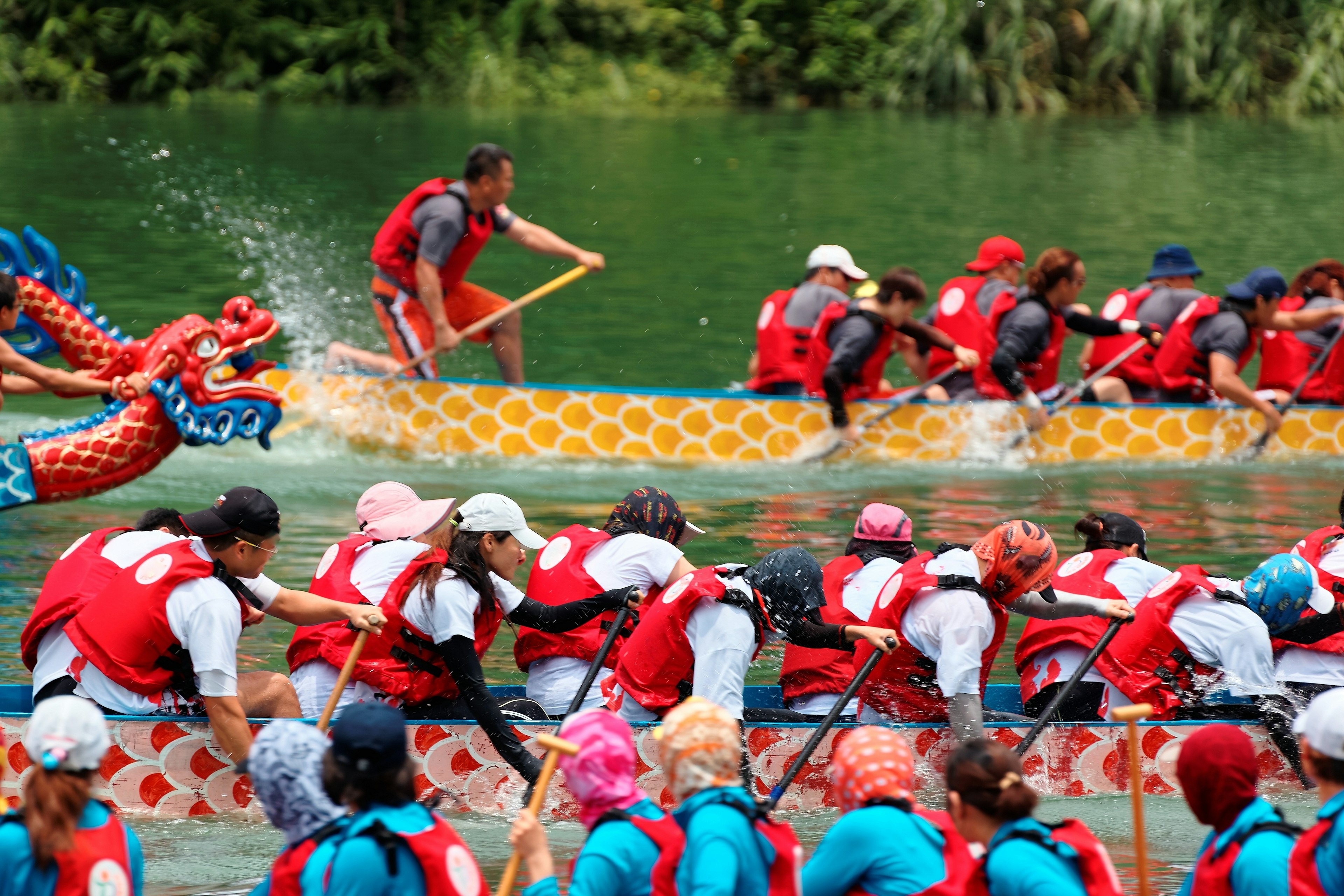 Scene of a competitive boat racing in the Dragon Boat Festival in Taipei, Taiwan, with a view of athletes pulling vigorously on the oars and competing strenuously in traditional colorful dragon boats.