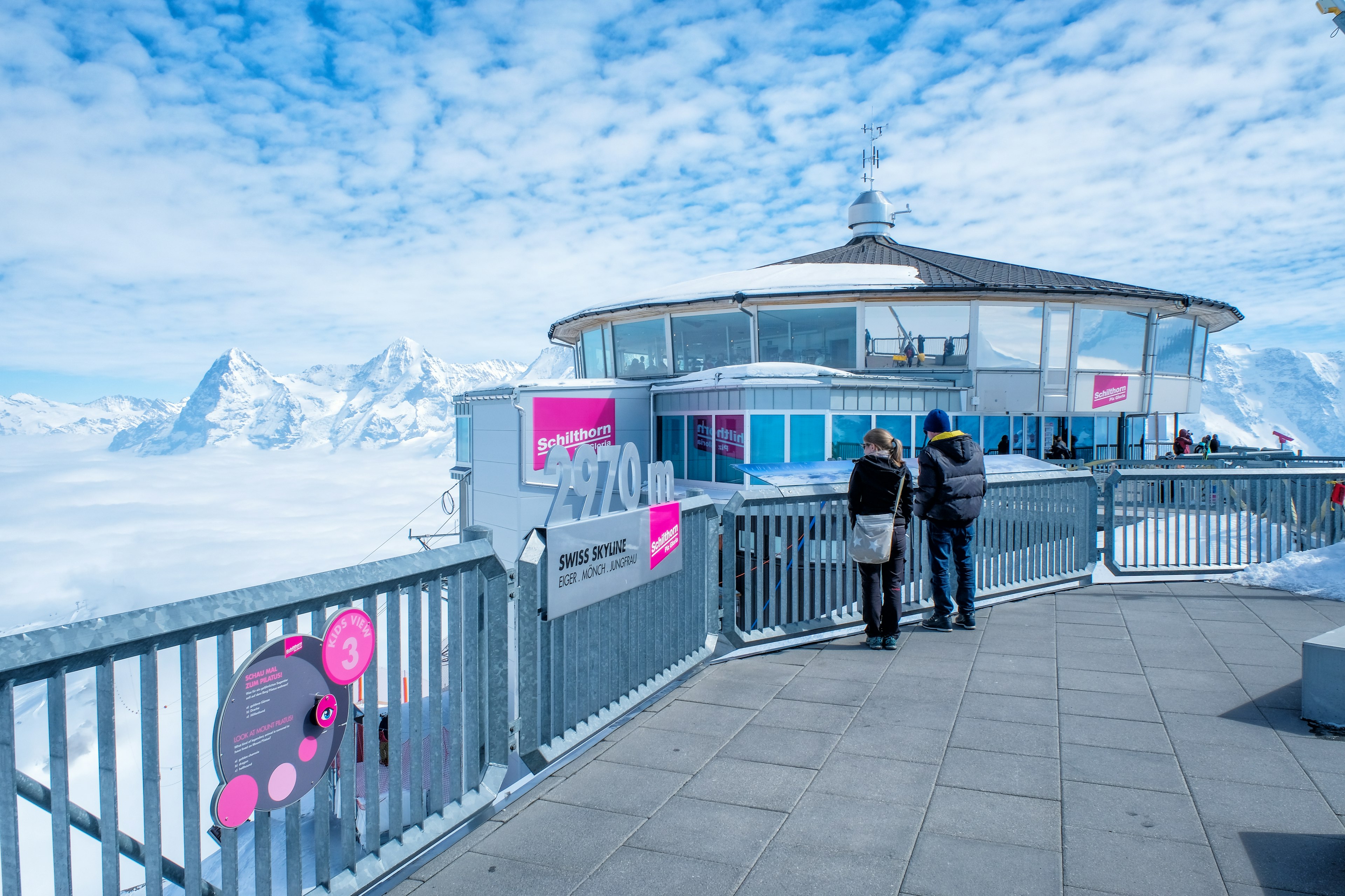 People at the top of the Schilthorn mountain enjoy the view of the surrounding mountains