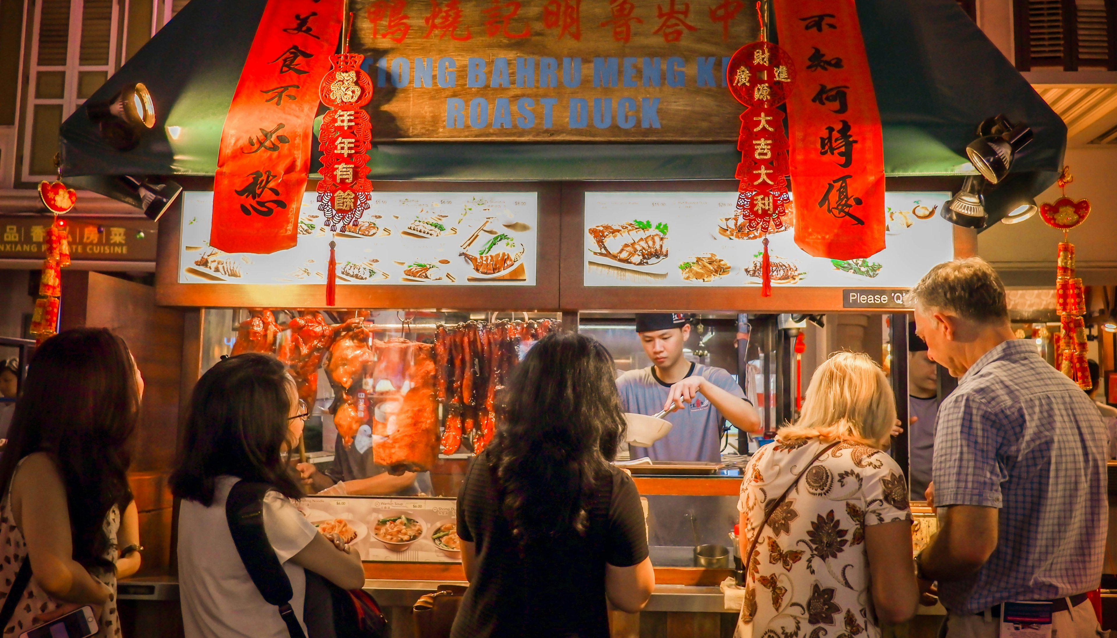 Image of crowded people in front of traditional noodle shop in Chinatown, Singapore.