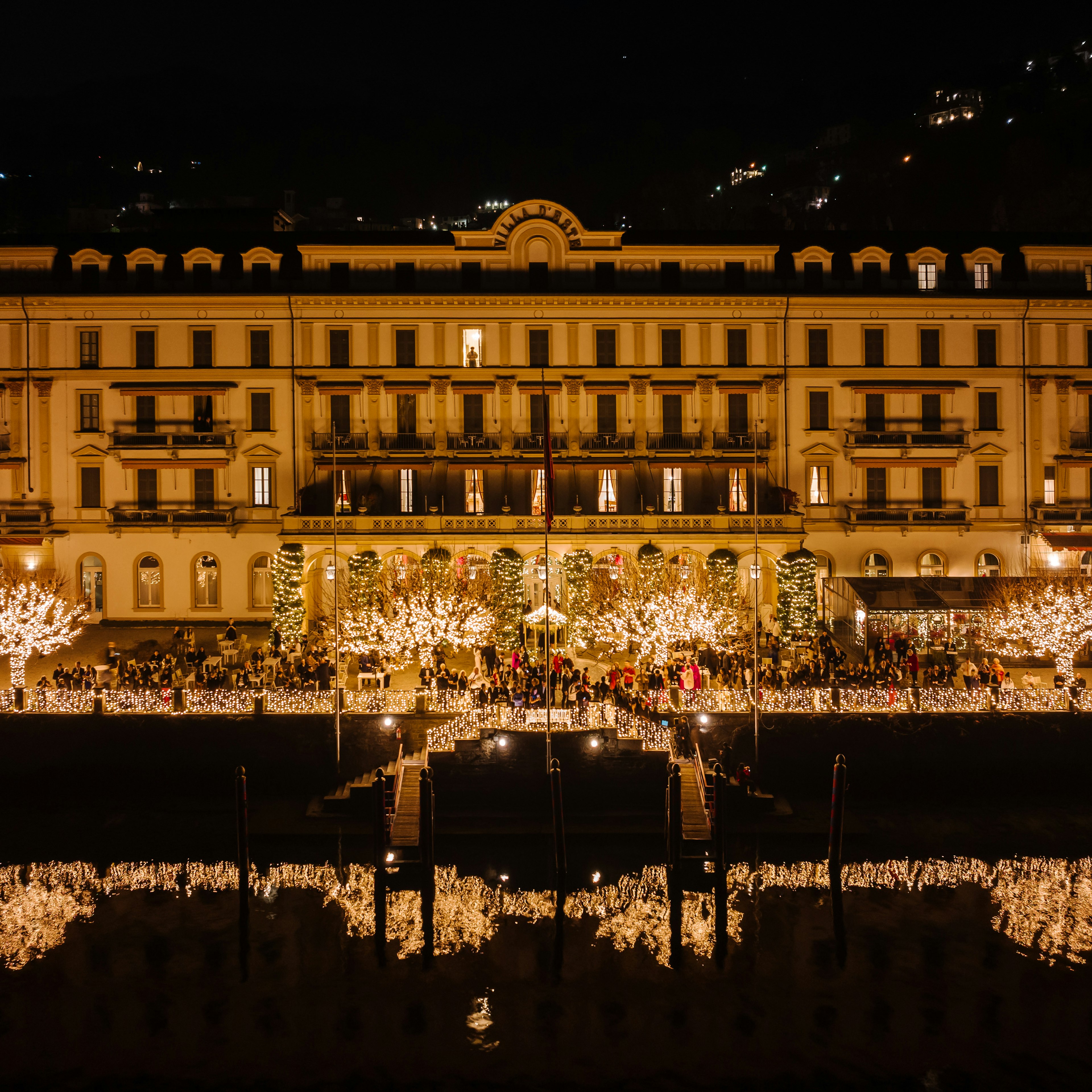 A lakefront property lit up in white Christmas lights that reflect in the water