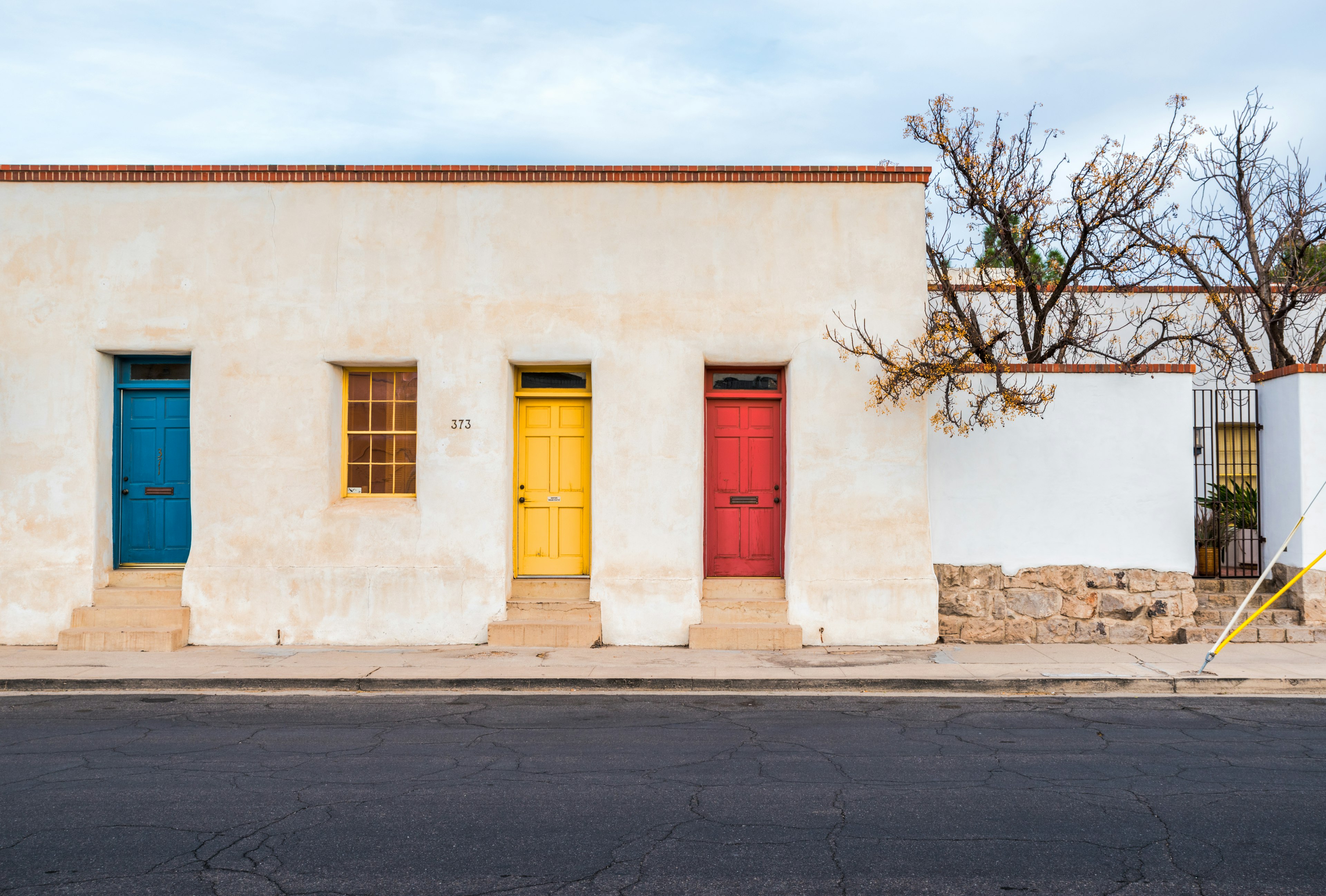 An adobe building with a blue, yellow and red door on empty street in Tuscon, Arizona, USA