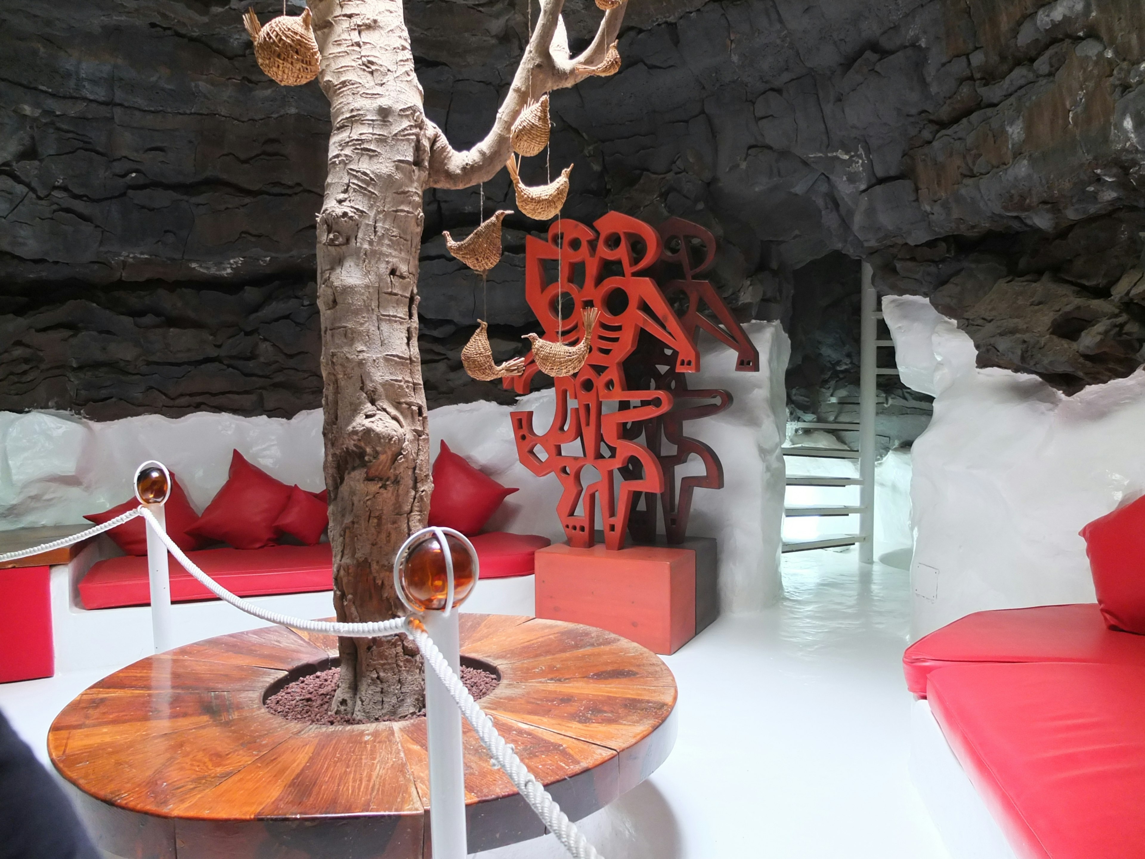 A room in a modernist home built into the side of a rock mountain with sleek red couch cushinos and artwork