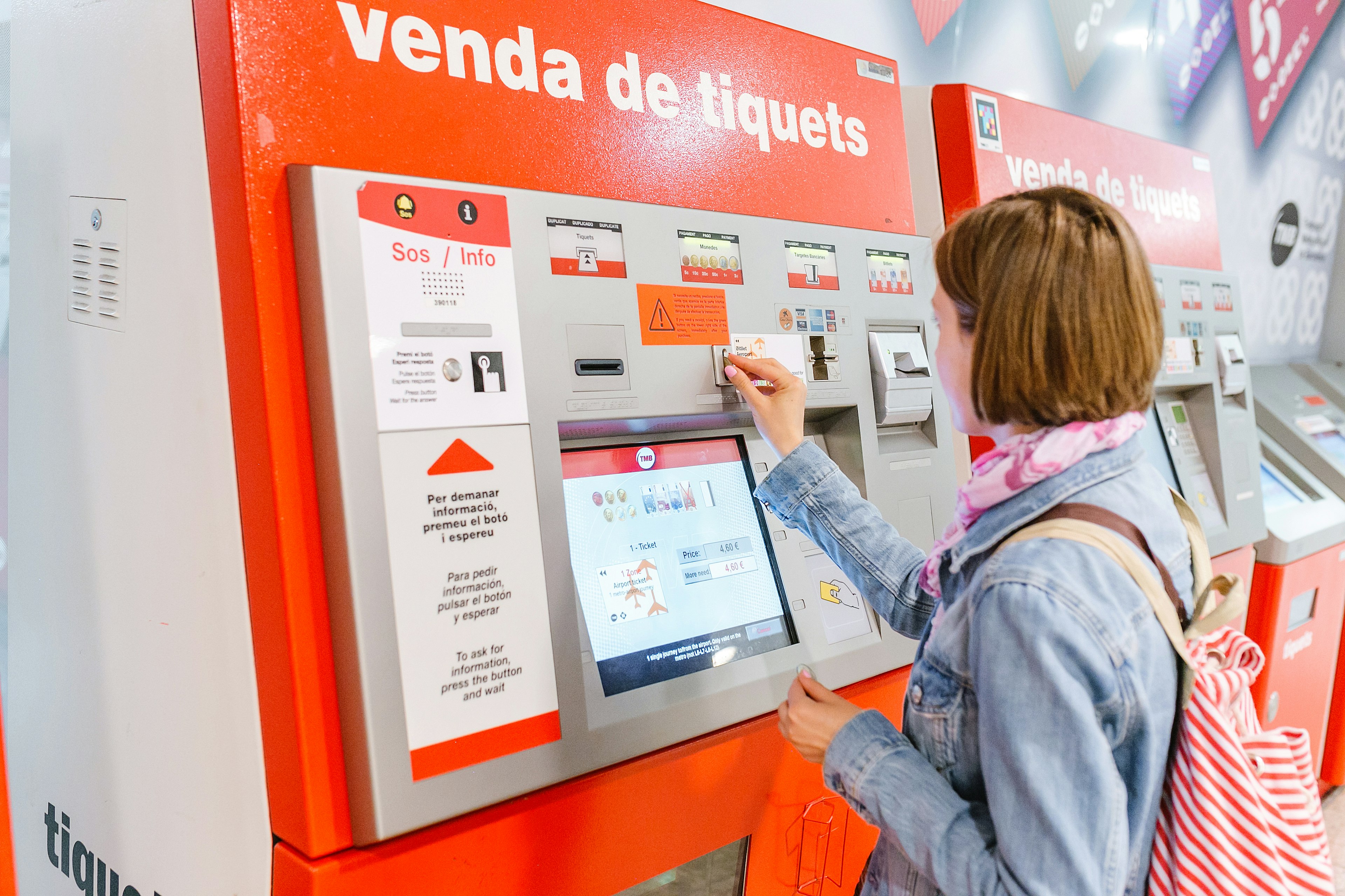 Traveler woman buying a ticket at a vending machine TMB at the metro station